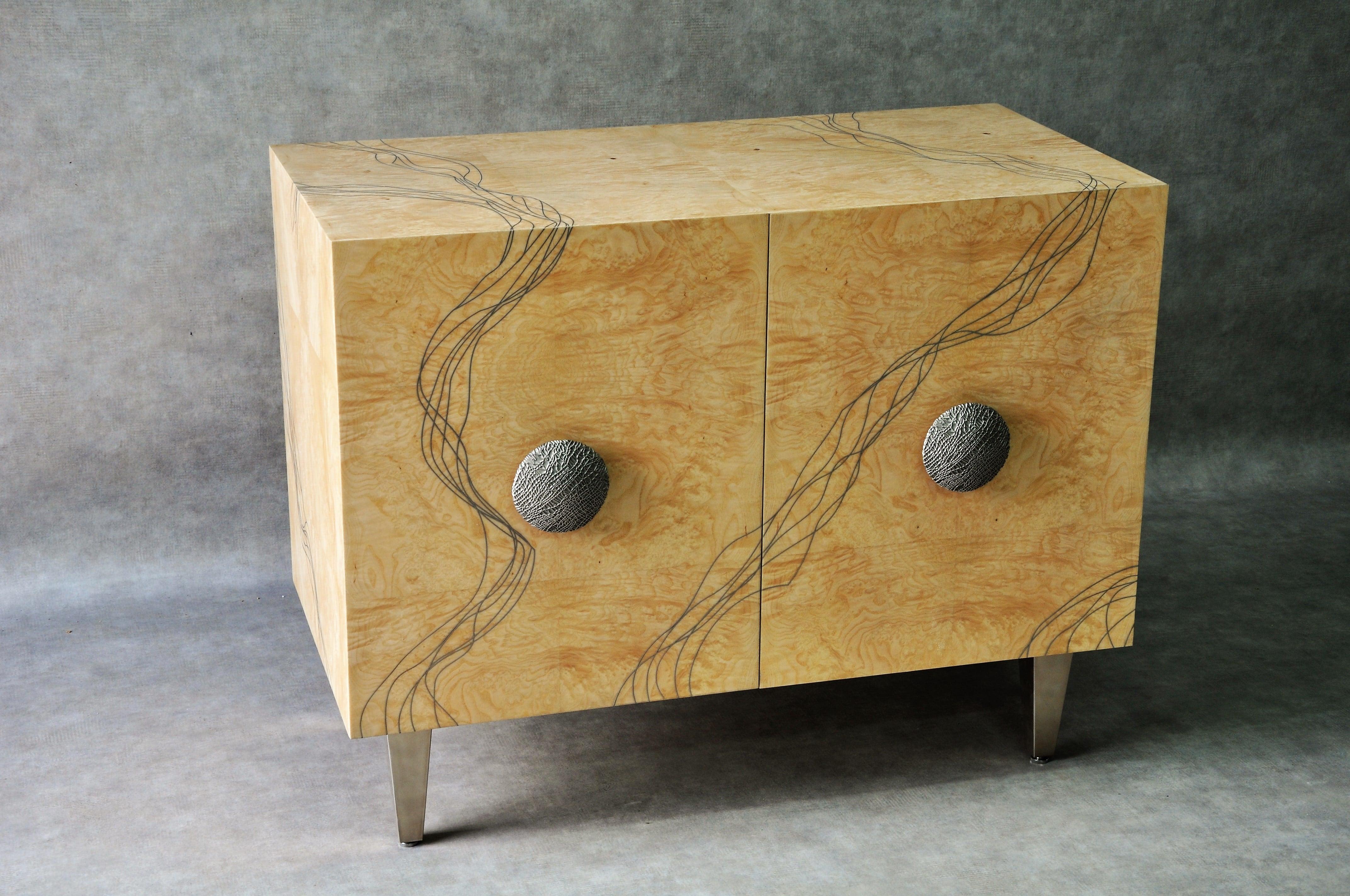 The Entrelacs sideboard is a unique item that encapsulates Frédérique Domergue's virtuosity in combining metal (here, polished titanium) and rare woods (burl ash). The interlaced patterns set into the veneer cover the entire cabinet (front and back)