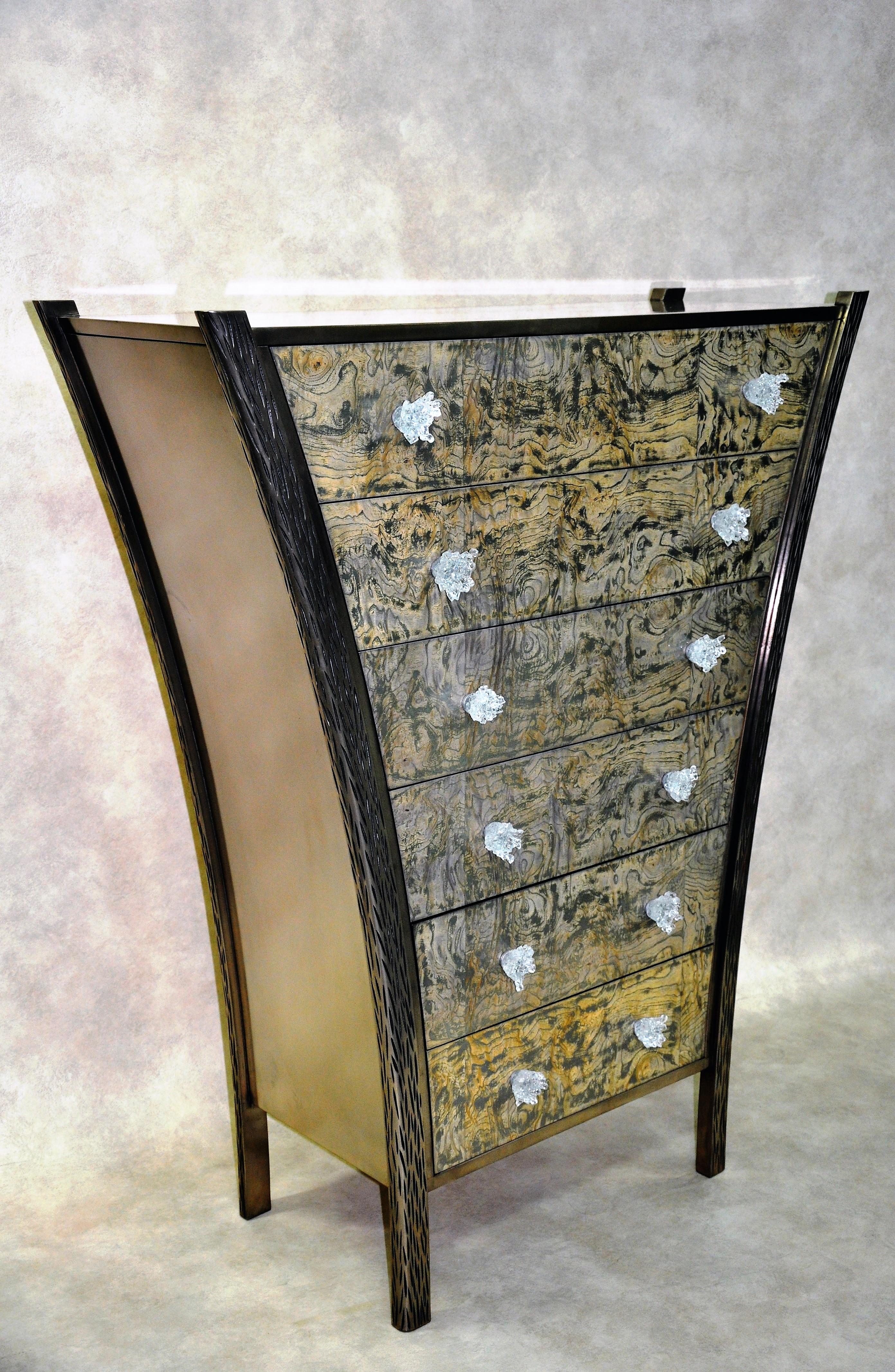 Polished titanium over wood.
Drawer fronts in Ash burl encrusted with titanium (titanium encrusted following the pattern of the wood). Handles in sculpted glass in the shape of flowers.
Dimensions: H 130 x W 110 x D 40 cm. Edition of 8 (2