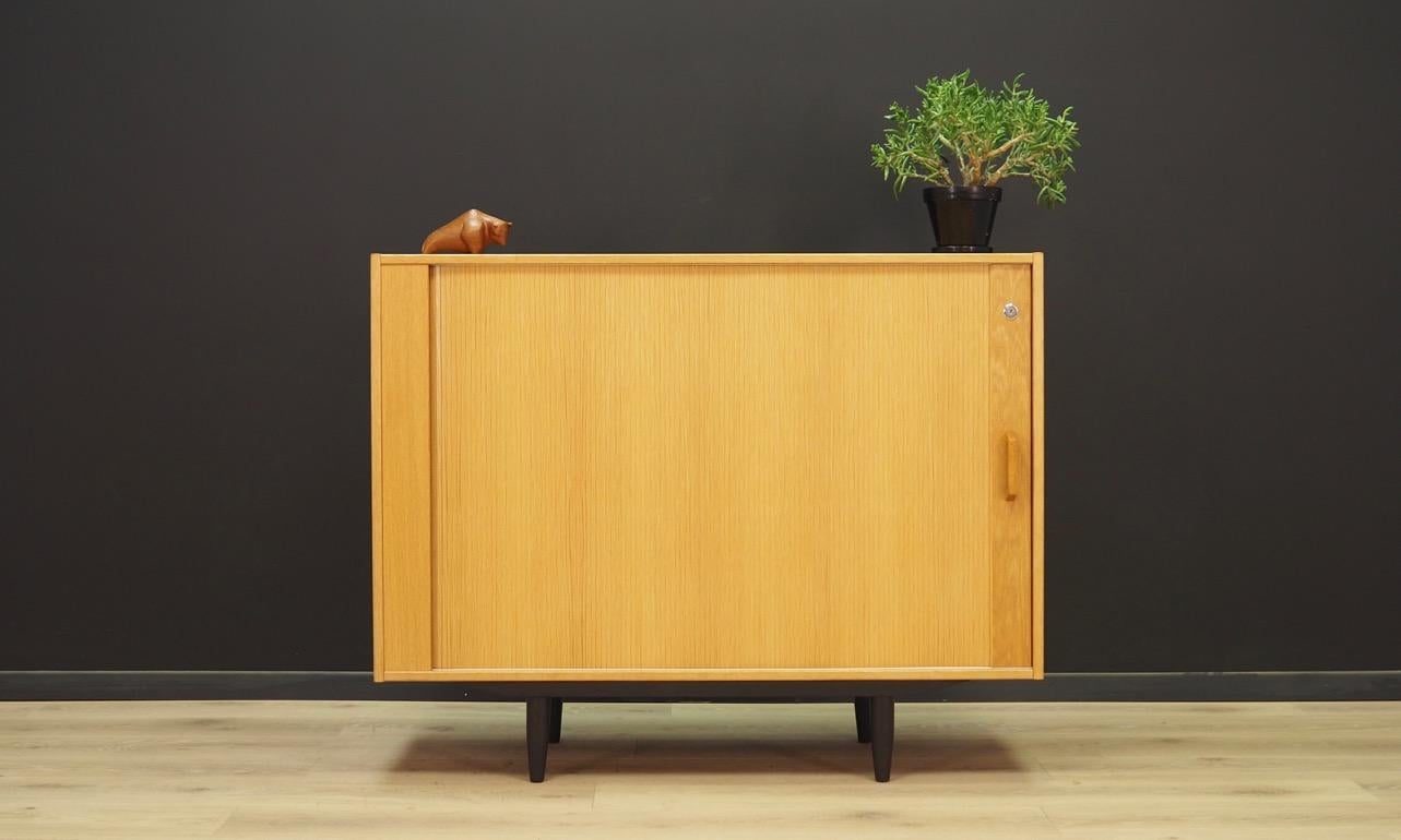 Fantastic cabinet from the 1960s-1970s. Minimalistic form, Scandinavian design. The surface of the furniture is covered with ash veneer. Two shelves adjustable in height behind the folding door. No key included. Maintained in good condition (minor