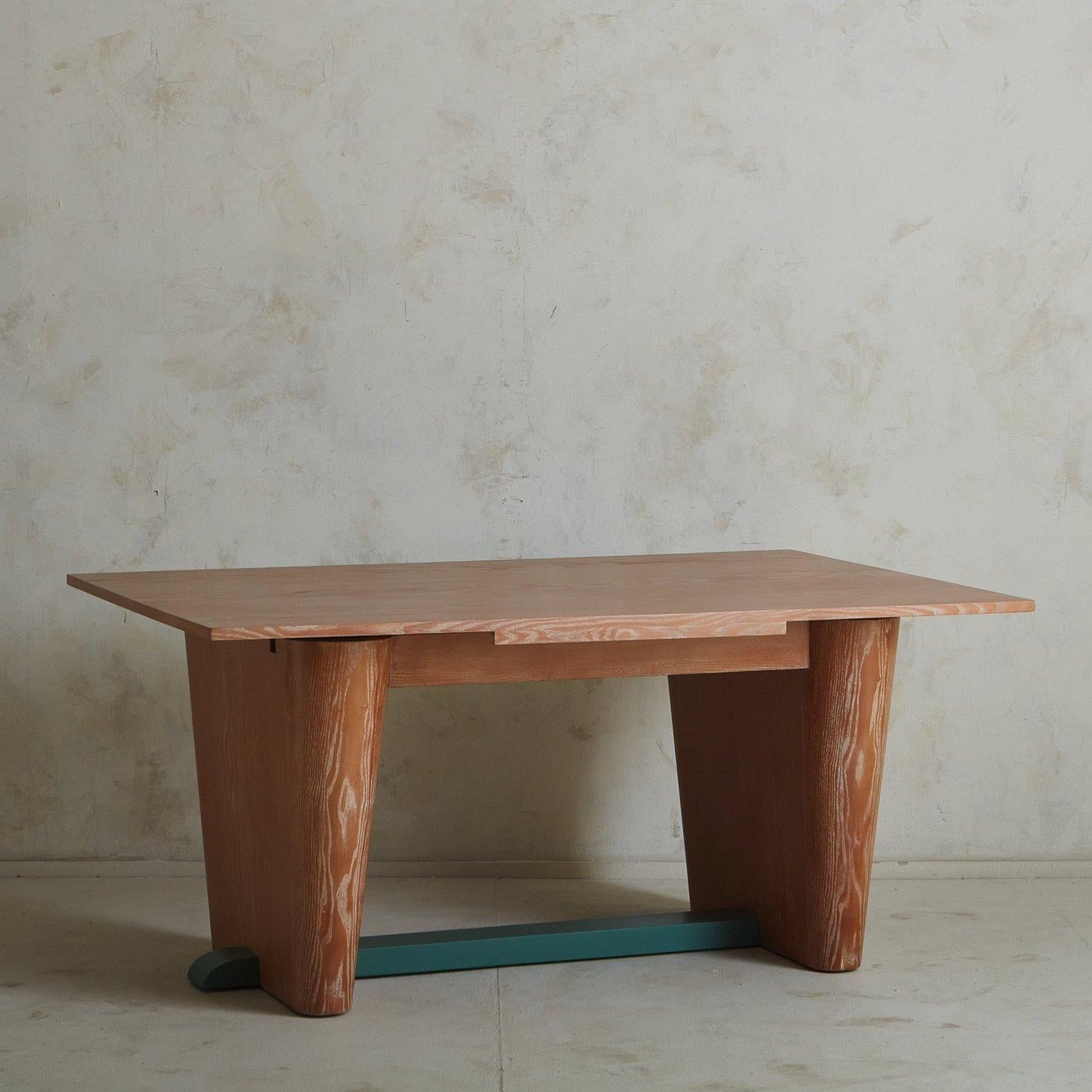 A 1940s French dining table or desk in the style of Jules Leleu. This table was constructed with ash wood and features a sculptural trestle base with a teal painted support bar. The ash wood has remarkable, painterly graining, which is emphasized by