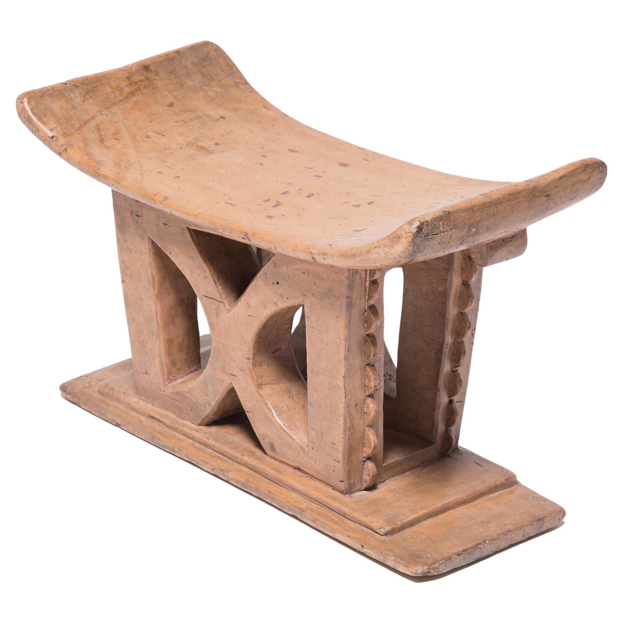 Stools indicated power, status, and lines of succession in traditional Ashanti culture. The tiered platform, curved seat, and ridged supports on this object reference the Ashanti King Stool. The gestural central symbol is a simplified and turned