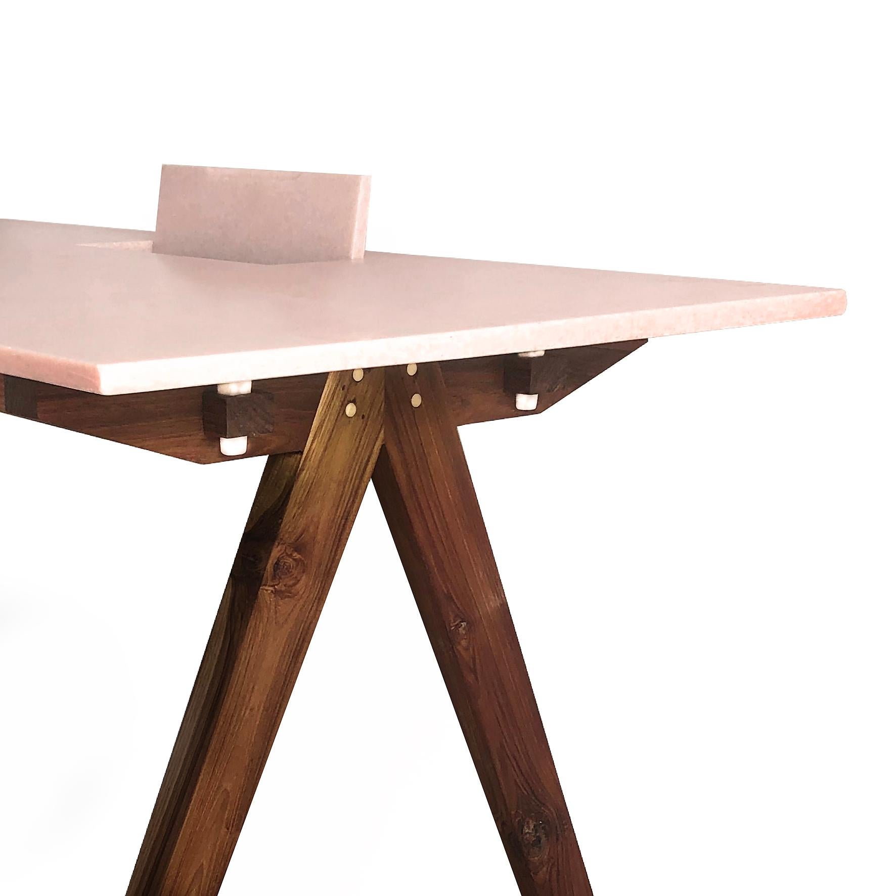 A rectangular wood and marble desk.
The tabletop is made out of Pink marble from Makrana. On a walnut rectangular support on four feet. 
The table is joined with white marble keys from Makrana and brass dowels. A hatch allows the storing of cables