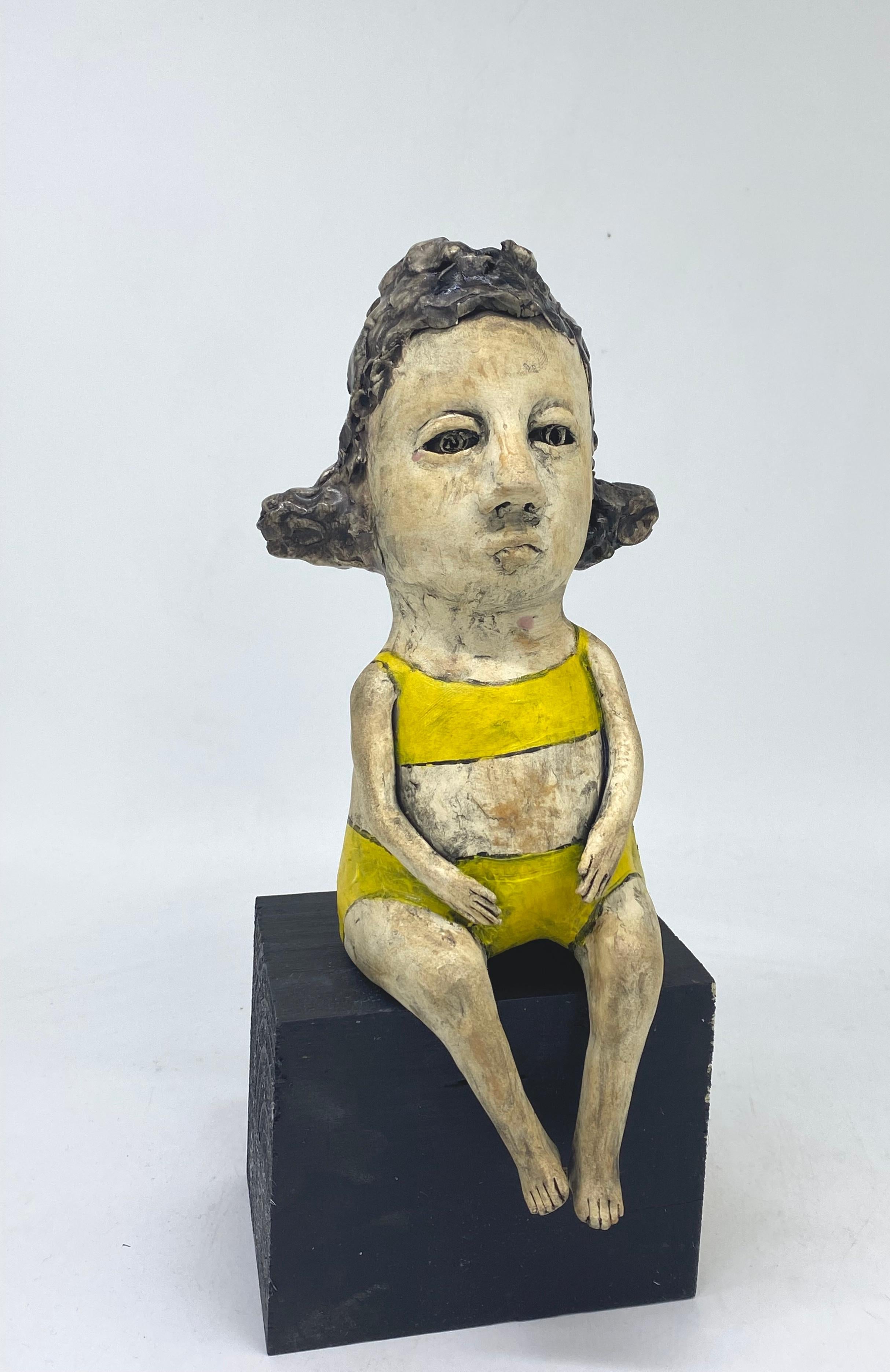 Ashley Benton Figurative Sculpture - Ceramic figure seated on wood block: 'Cheer up'