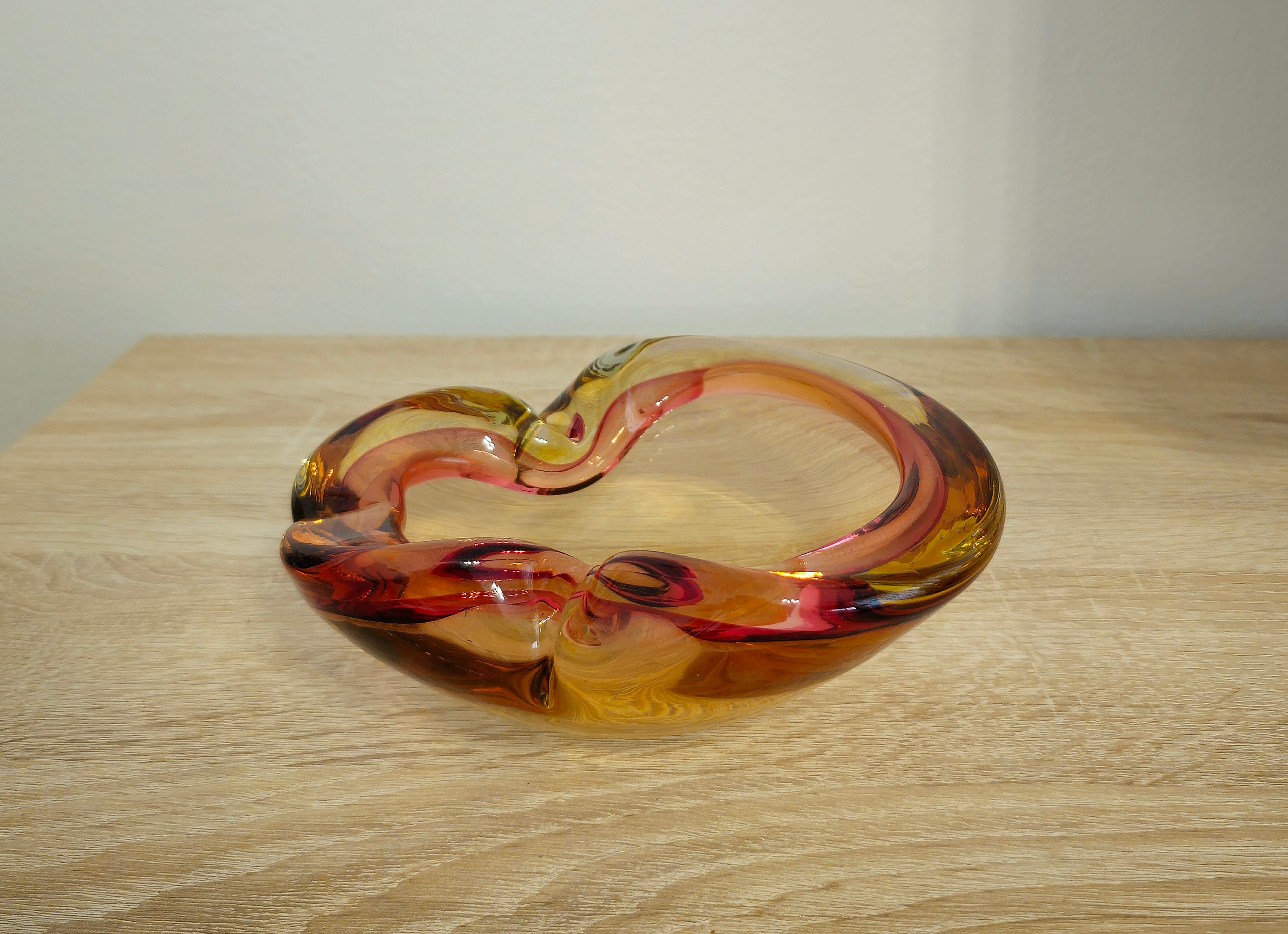Ashtray or bowl attributed to the well-known Italian designer Archimede Seguso and produced in Italy in the 60's/70's
The ashtray was made of Murano glass in shades of amber and pink with the famous 