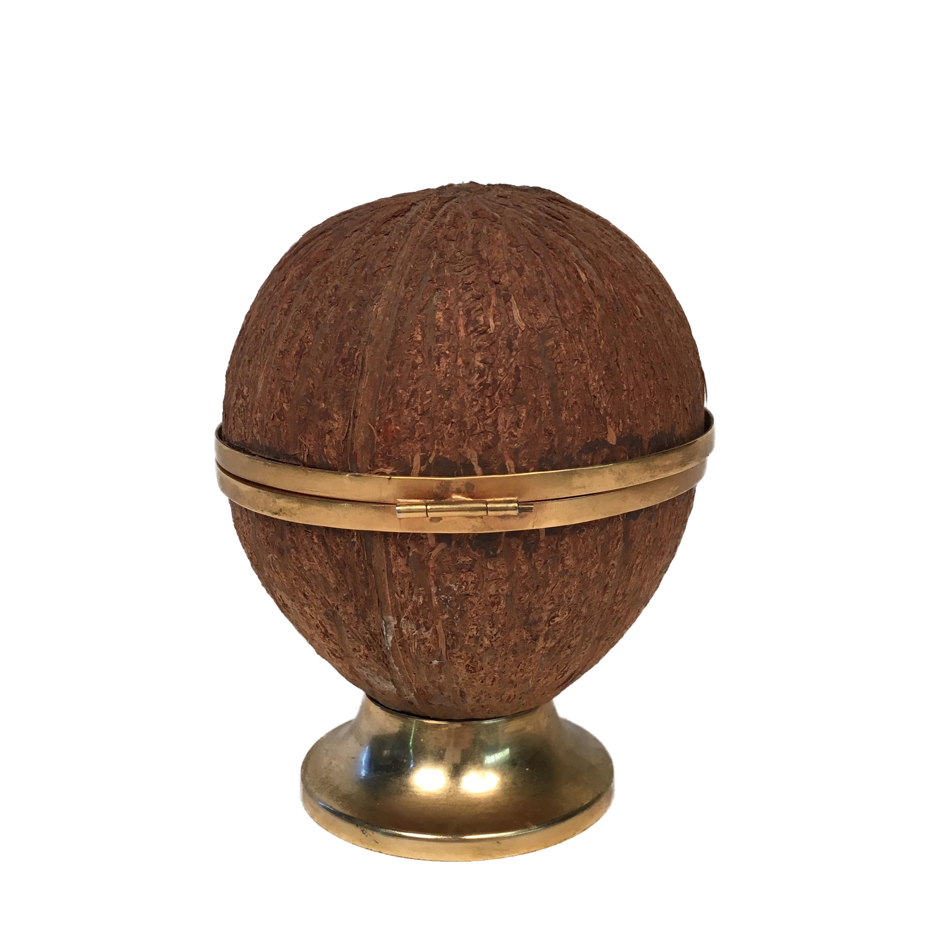 This wonderful ashtray was made from a real coconut and its interior is covered by brass. It rests on a base also in brass.