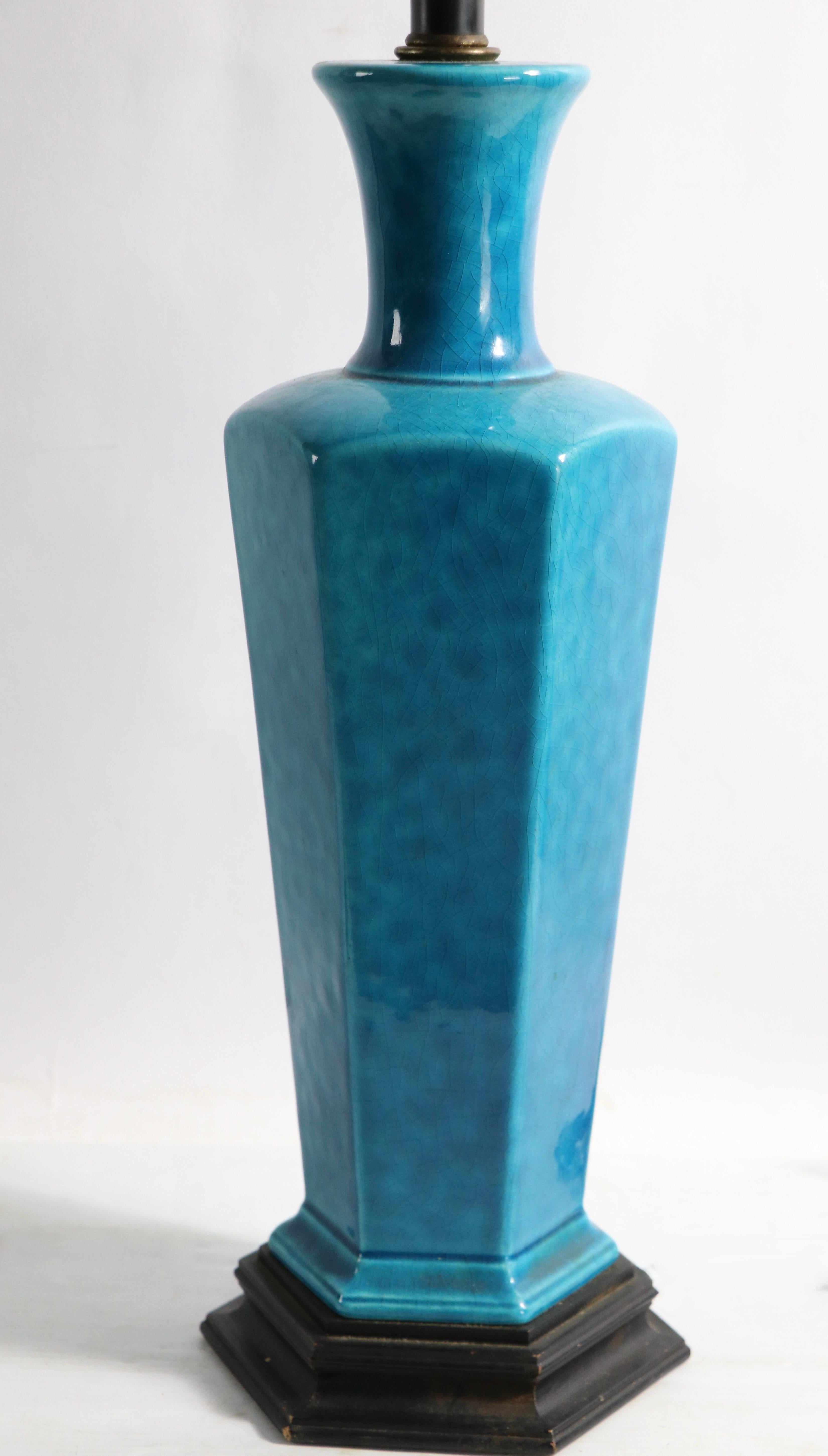 Stylish Chinese influence mid century table lamp in stunning blue glaze, on black painted wood base. The lamp is in very good, clean, working condition, shade not included.
 Measures: Total H 34 x H to top of ceramic base 19 x 7 Wx 6 D inches.