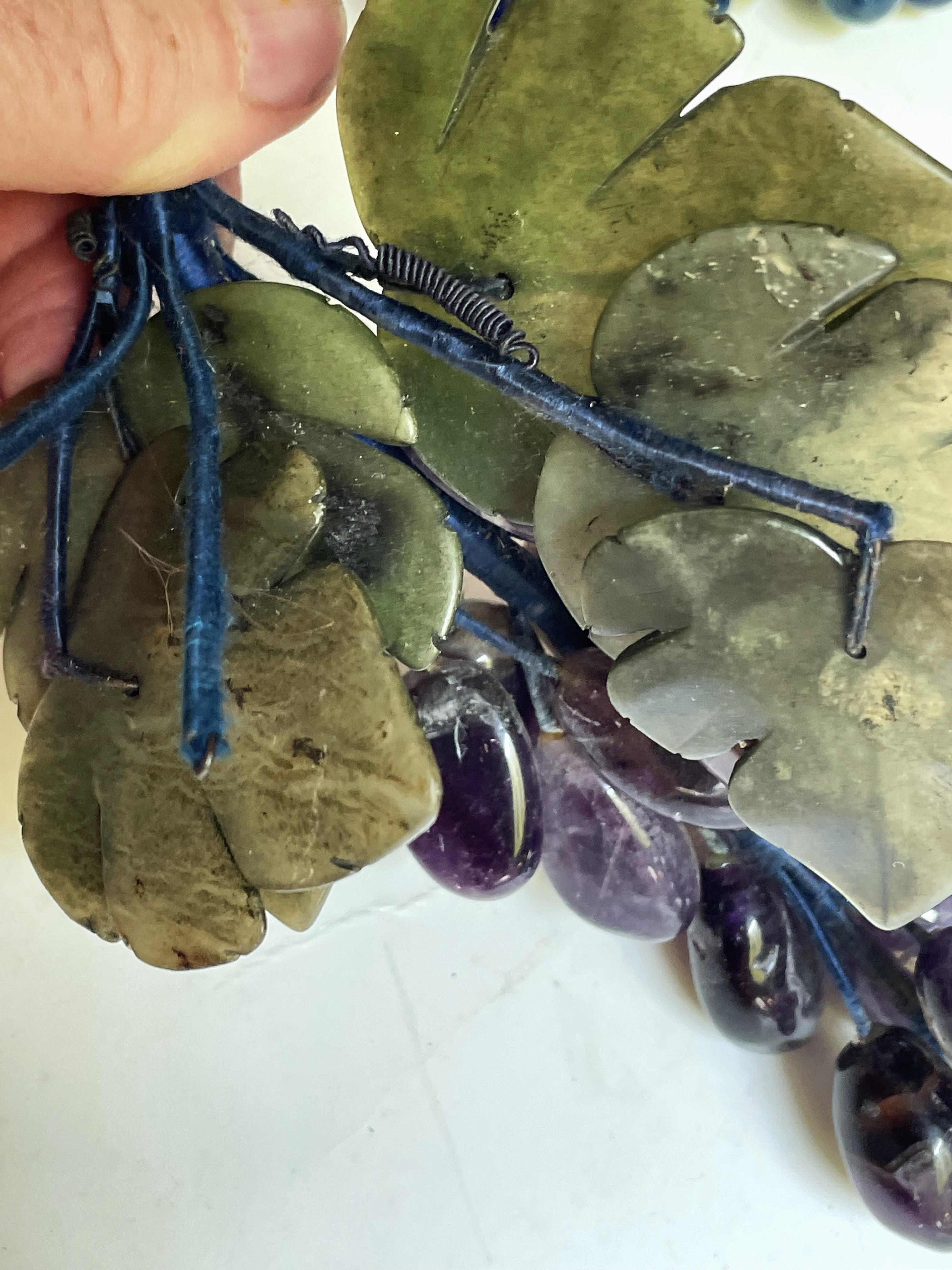 Se trata de un fabuloso racimo de uvas de amatista talladas de diversos tamaños y formas, con fantásticas imperfecciones e inclusiones que se utilizan para dar a las uvas un aspecto aún más realista. Las uvas están unidas al tallo por un alambre