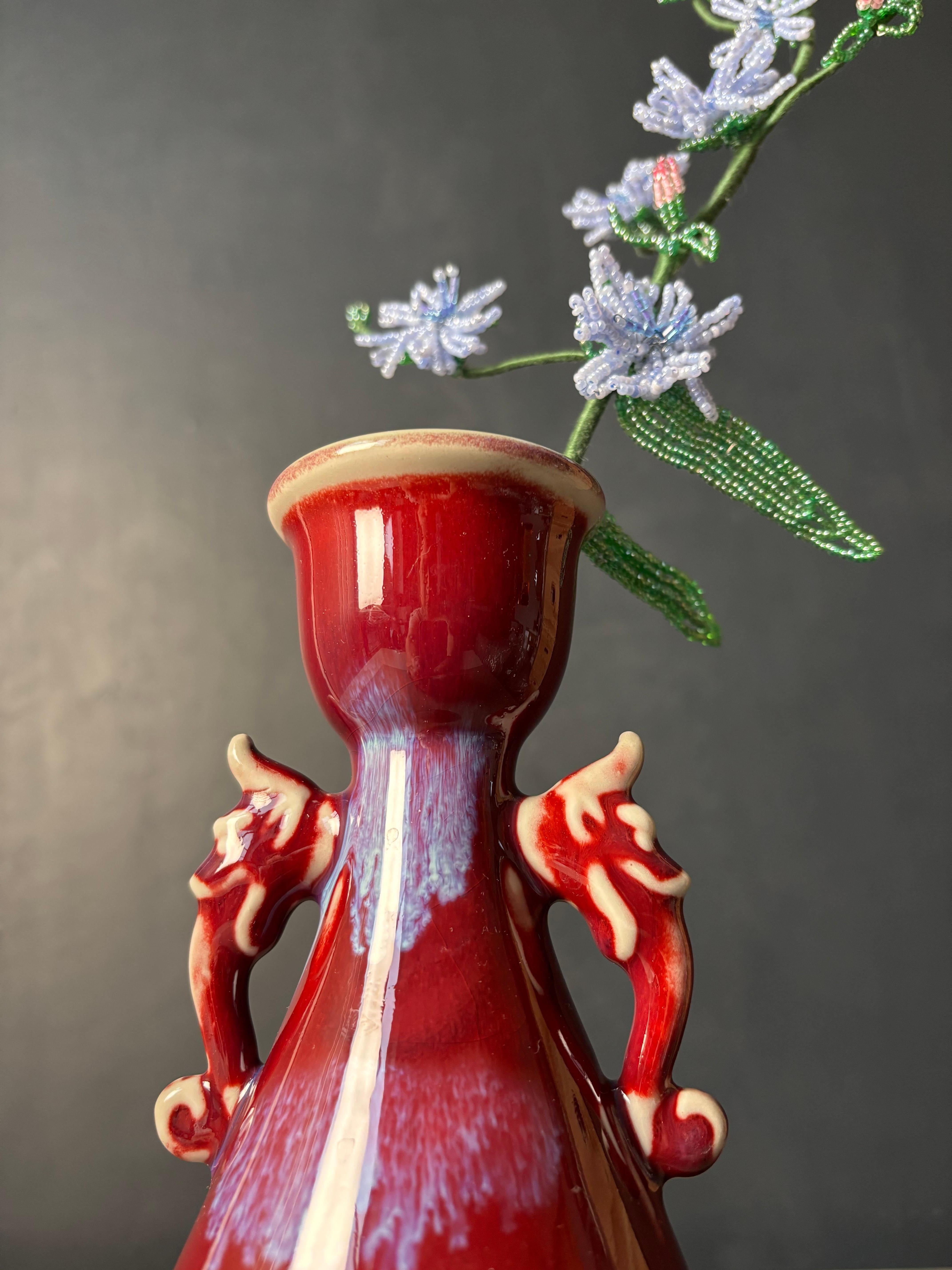Soft shaped vintage Chinese vase with dragon handles. Thick and shiny maroon glaze with cream white accents and splashes of lilac. 
Beautiful vintage condition. 
China, circa 1940s-1950s. 