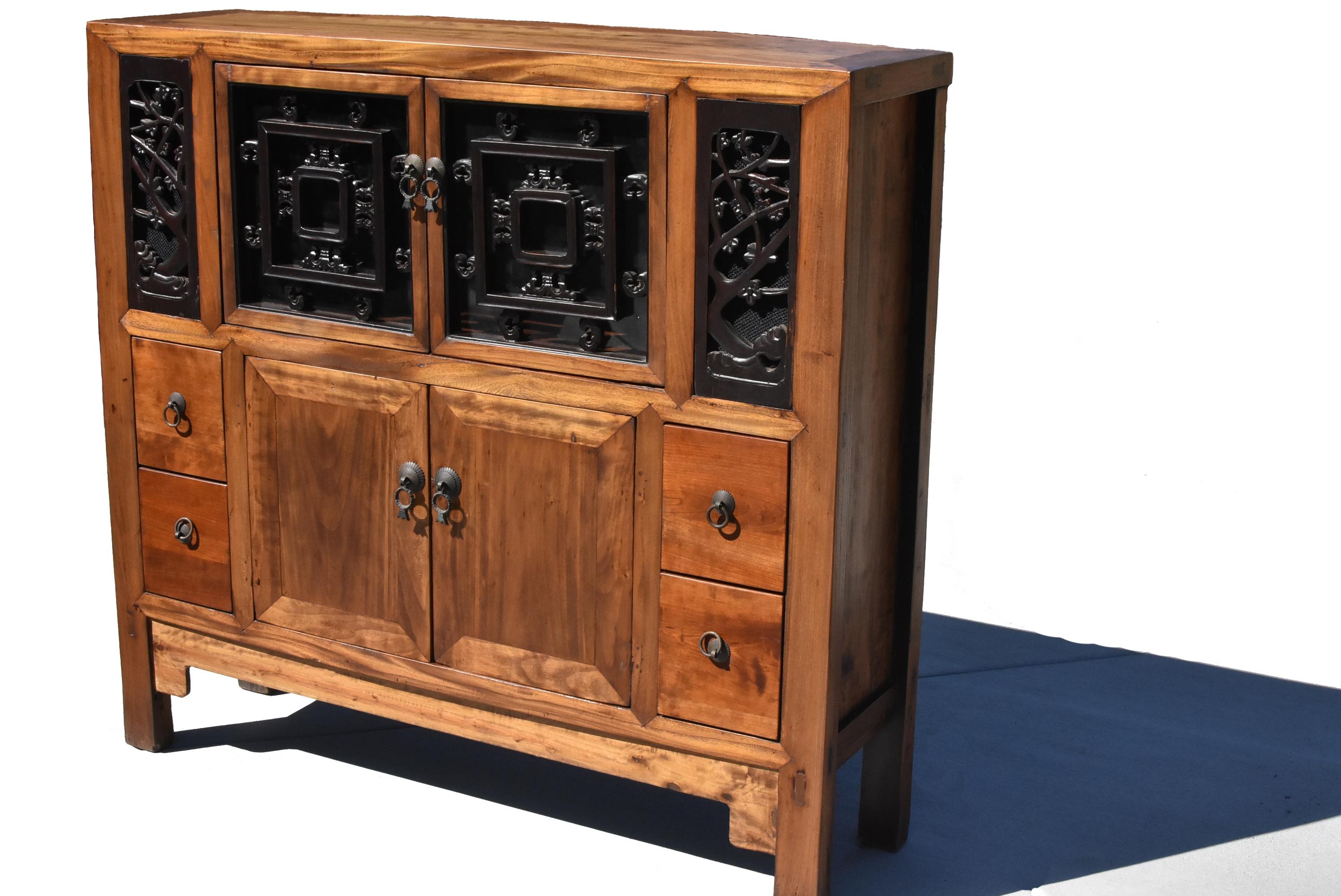 A beautiful Chinese book cabinet, made of solid wood in mitered tenon and mortise construction. Top doors and side panels feature carved antique screens backed by mesh and glass. The carvings depict plum tree blossoms and butterflies. The bottom