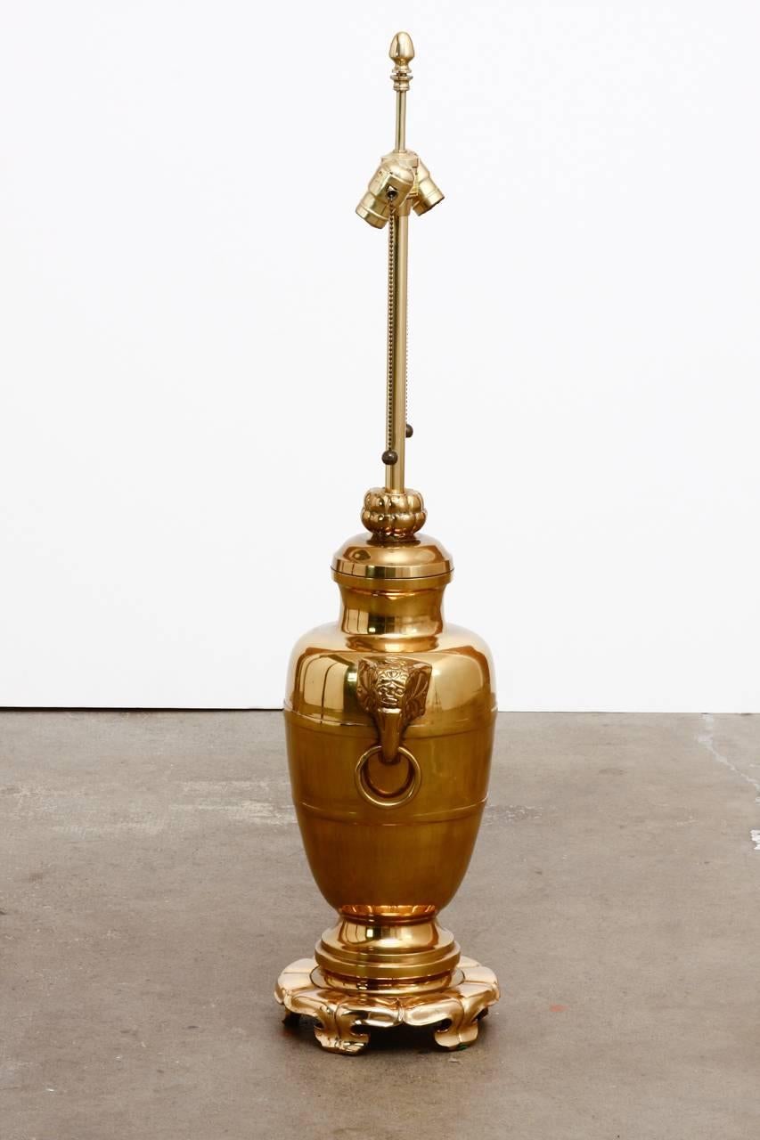 Fantástica urna o jarrón asiático de latón con asas de cabeza de elefante convertida en lámpara de sobremesa por Marbro Lamp Co. La urna está montada sobre una base de latón con forma de flor de loto y rematada con un herraje de latón de doble