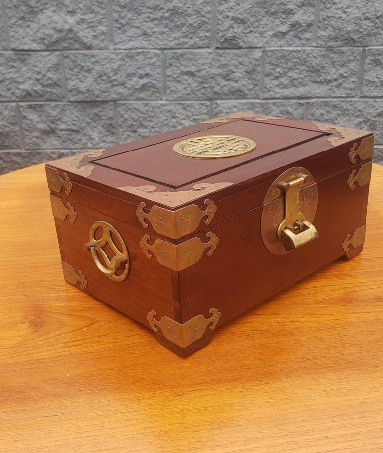 This is a Chinese jewelry box that is made out of rosewood with beautiful Chinoiserie brass trim. It is a nice heavy box that measures 13”W x 8”L x 5 1/2”H. The top layer inside holds 6 small compartments and 10 ring slots, the bottom layer has 3