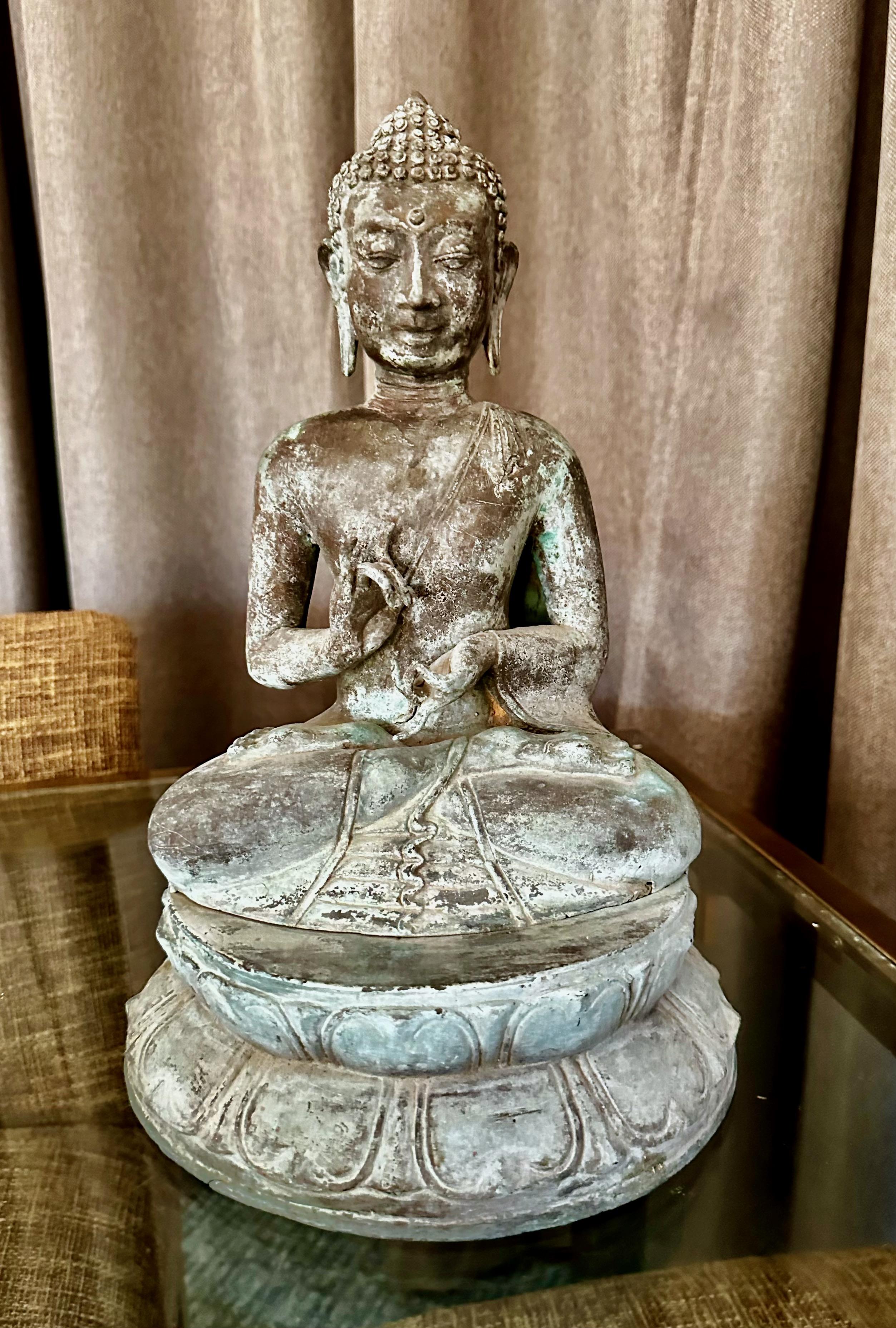 Asian patinated brass or bronze seated Gandhara Style Buddha with both hands raised in the vitarka mudra or teaching hand position.