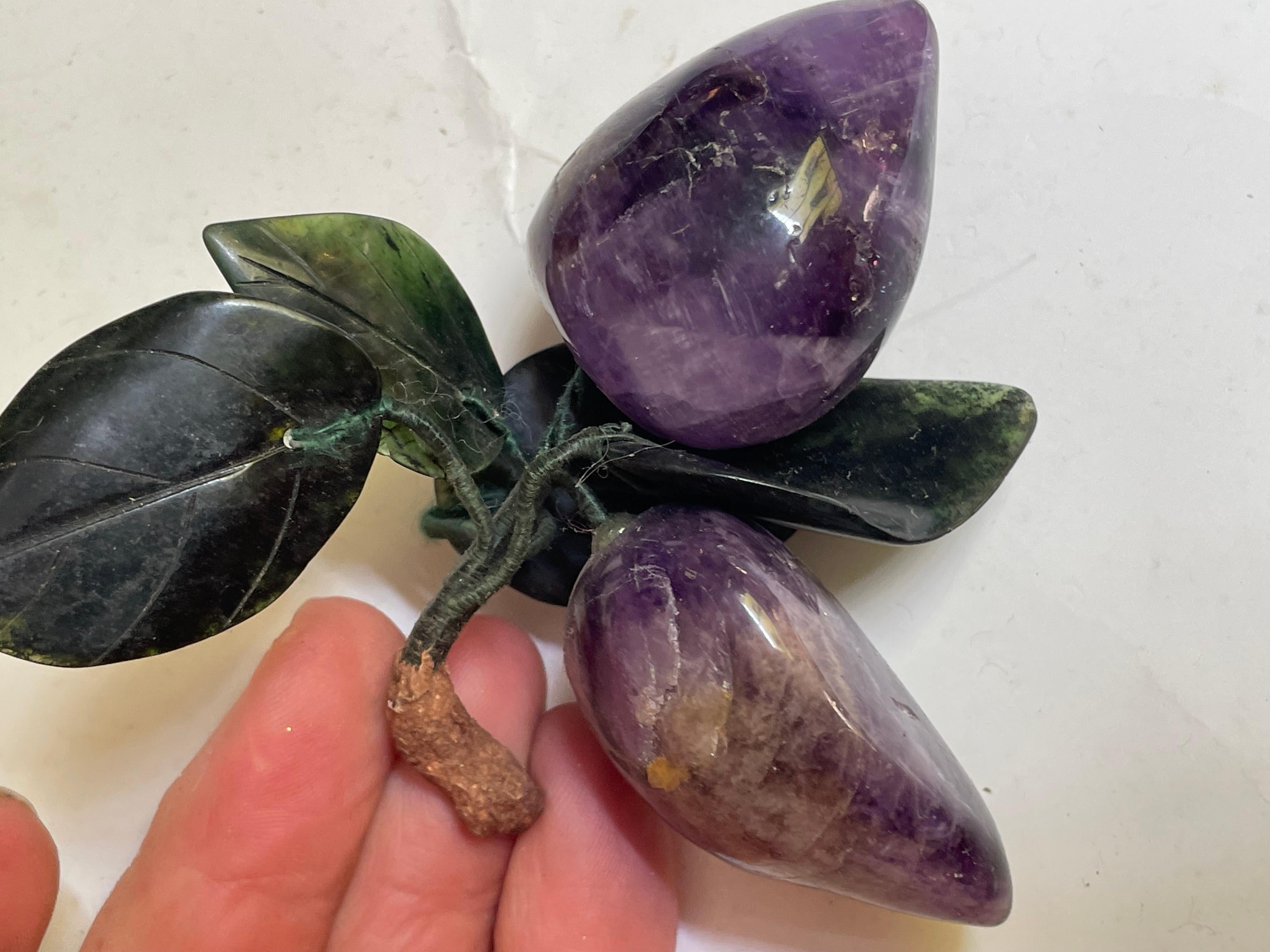 This is a great little pair of amethyst carved plums connected by wrapped wire stems to carved jade leaves and a brown stem. The fruit measure 1 1/2 inches by 1 3/4 inches and 2 inches by 1 1/4 inches and the leaves measure 1 1/4 inches to 1 3/4