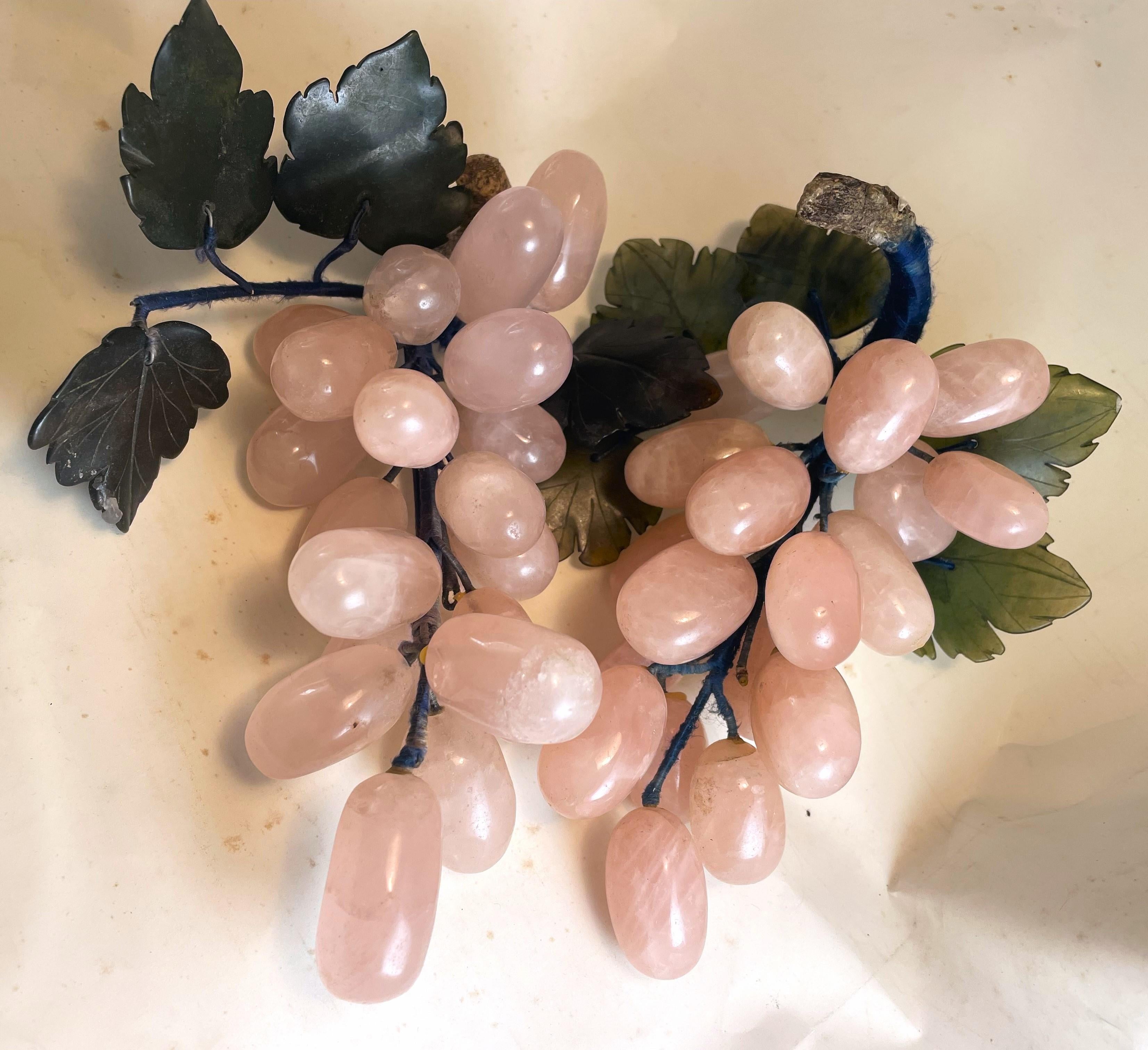 These are a lovely pair of carved rose quartz grape bunches with dark green jade leaves and wire stems that are wrapped with satin cord and have a faux wood end where the grapes would have been cut from the vine. There are wonderful natural