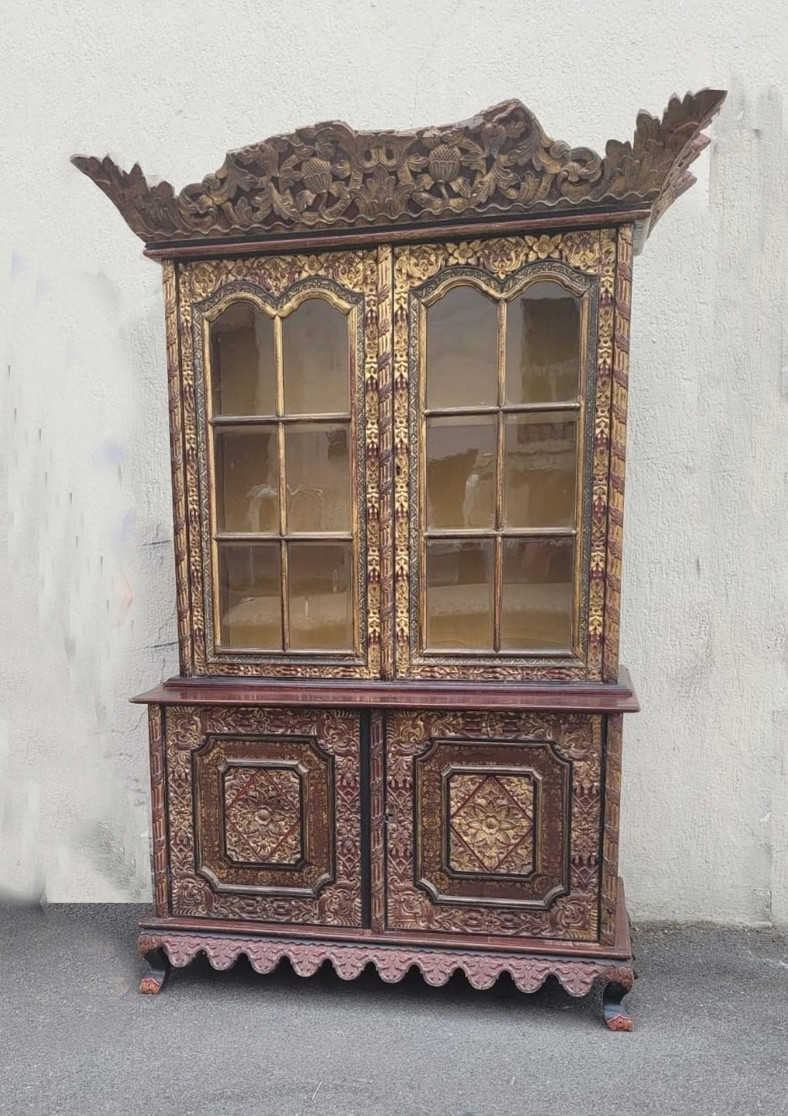 Two-part piece of furniture in carved and lacquered / gilded wood, composed in the upper part of a display case opening with 2 doors with small panes, and a lower part with 2 fully carved doors.

The sides are decorated with floral compositions
