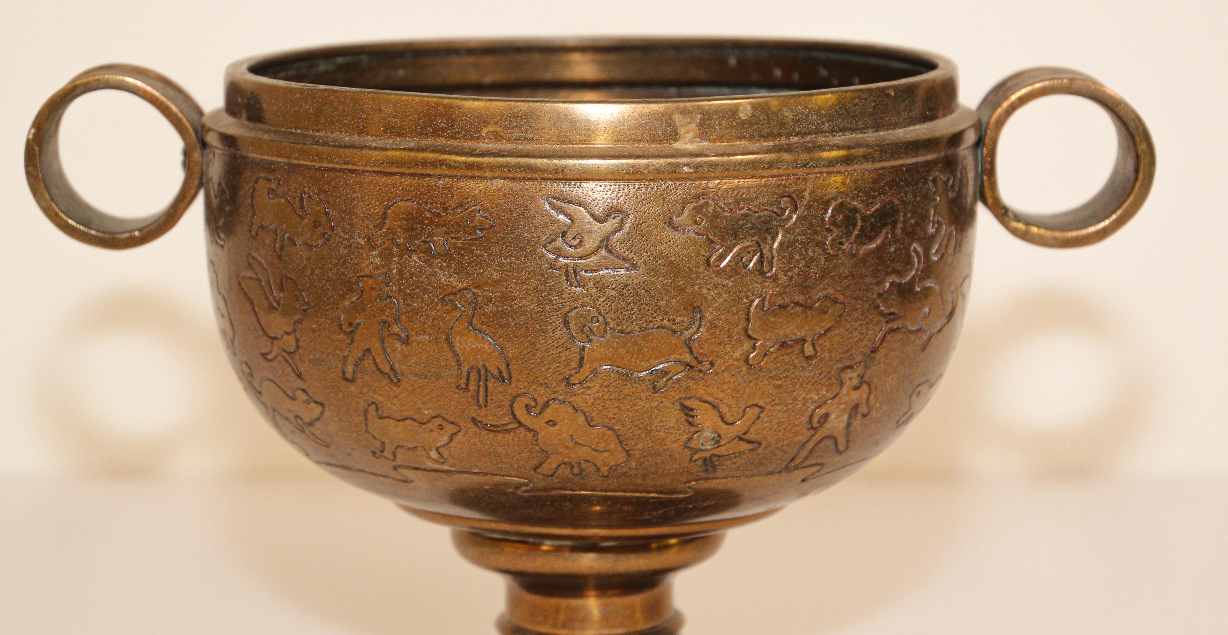 Large cast brass Asian footed bowl with two handles.
Could be used as a jardinière for an orchid composition.
Engraved brass with animals designs on brass vessel.
Great heavy brass Chinese art metalwork collectible object.
Top opening 6.5