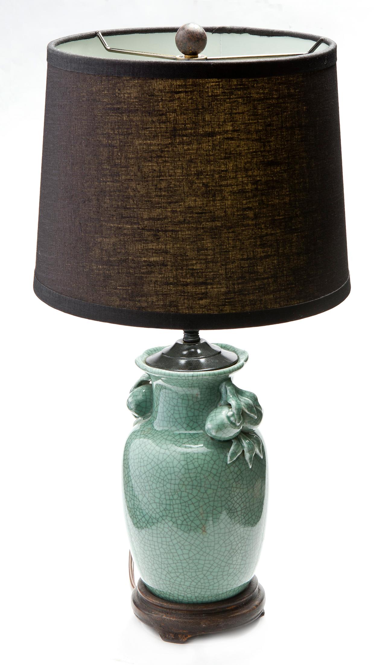 Charming diminutive Asian celadon vase/lamp on ebony wood base. The celadon vase features ornament design on each side. The lamp is sold with black linen shade with gold lining. Simple brass finial is included. 
The shade measures as follows:
10