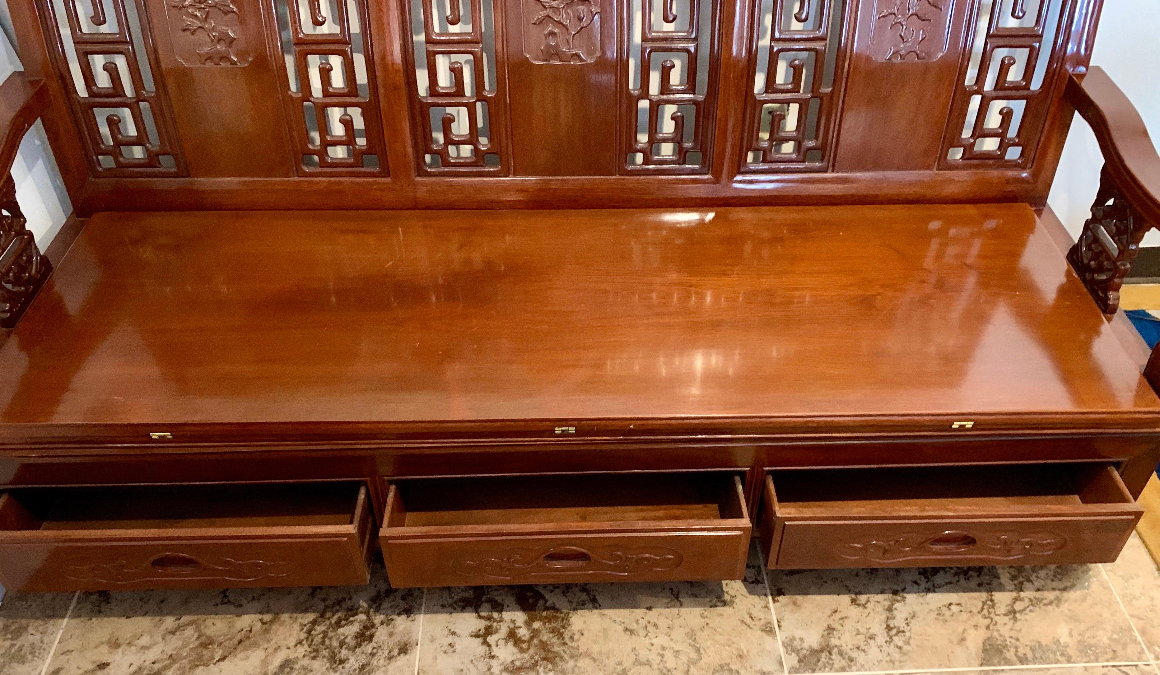 Magnificent Chinese carved bench daybed handcrafted of rosewood with hand carved pierced open fretwork on back and arms. The back also has a hand carved floral motif. There are three drawers underneath. The seat folds open to a bed which is