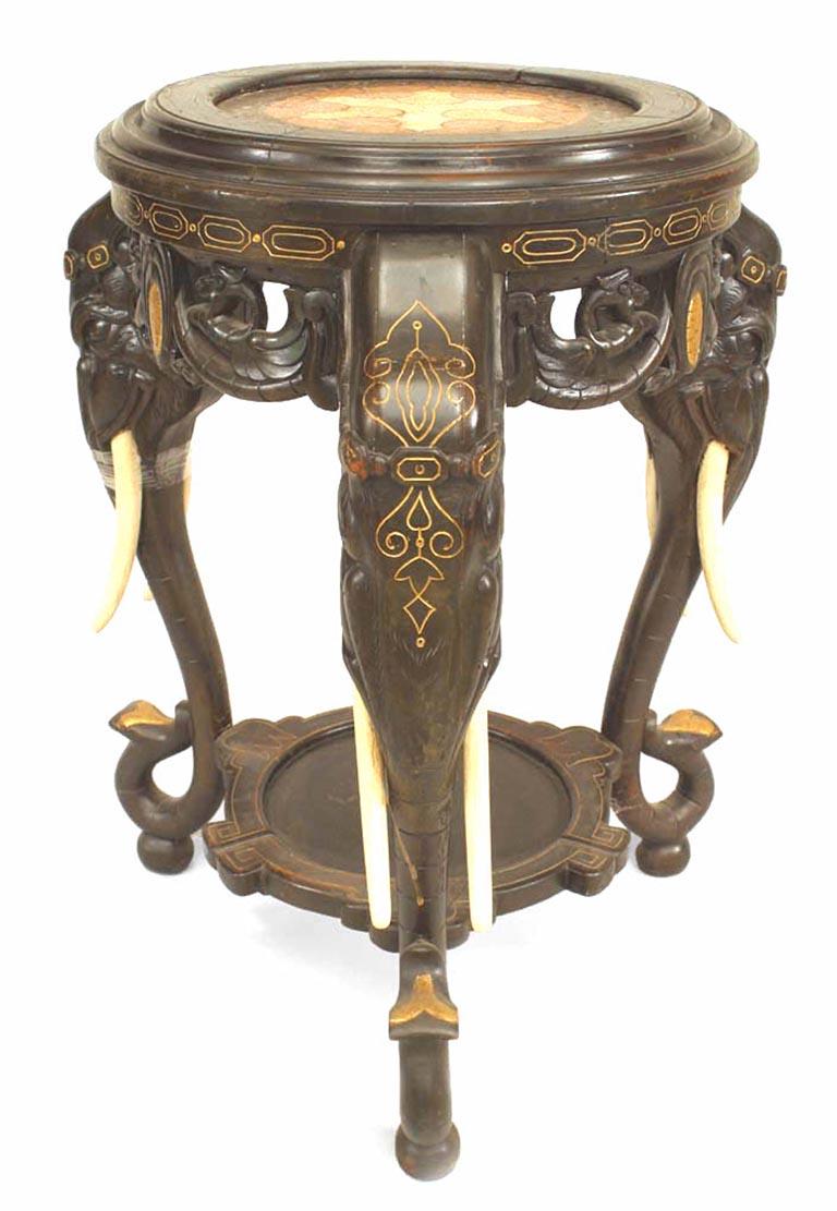19th century Asian Chinese style ebonized and gilt incised trimmed pedestal table with 3 elephant head legs and inset inlaid round marble top with shelf stretcher.