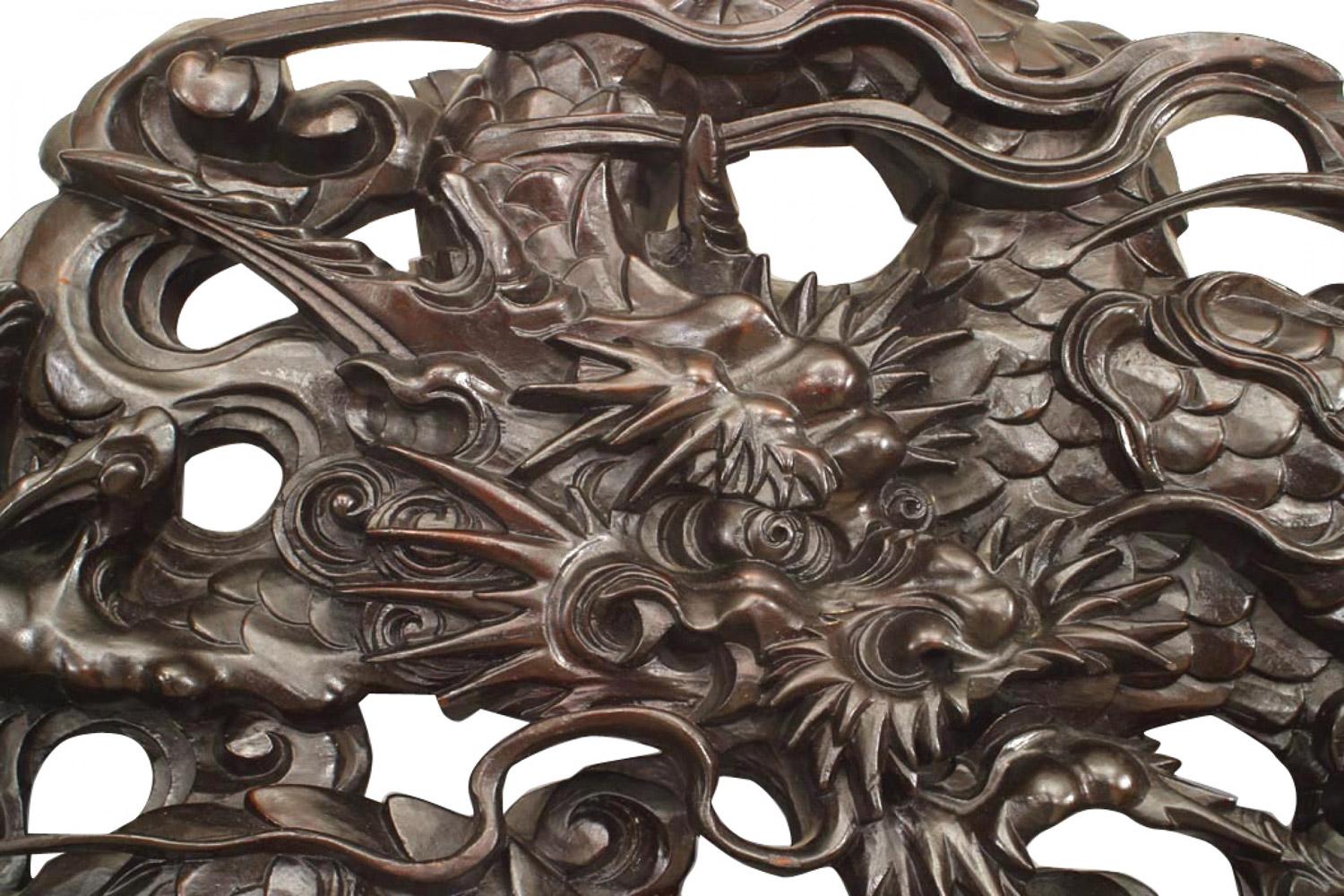 Miroir mural de style asiatique chinois (19e siècle) en acajou et verre biseauté, avec un cadre sculpté à décor de volutes et un fronton filigrané surmonté de dragons sculptés.