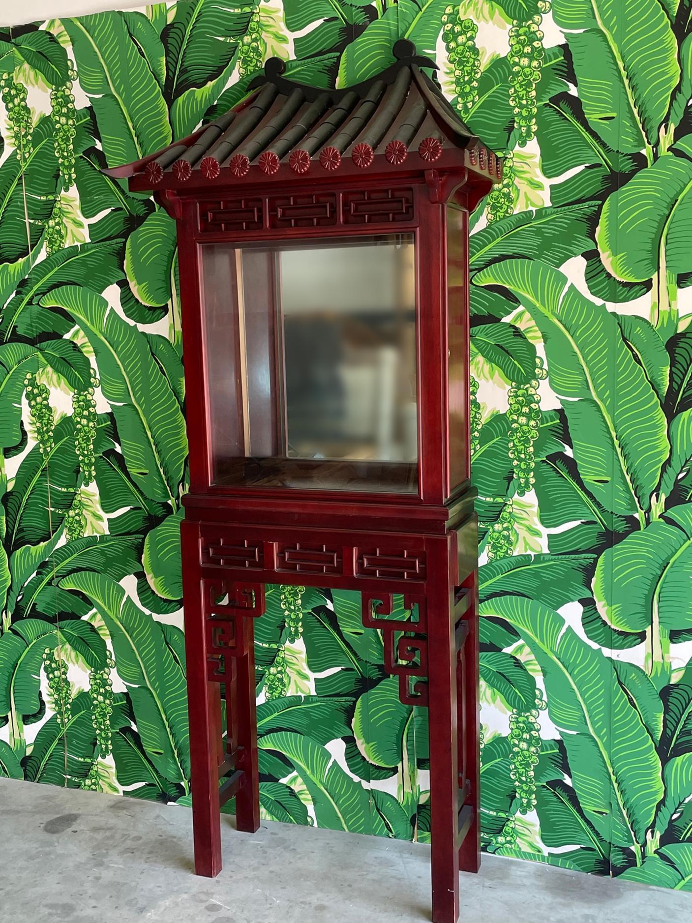Asian style display cabinet features Chinese pagoda roof and fretwork stand. Interior access from locking side door. One drawer on each side of stand. Good condition with imperfections consistent with age, see photos for condition details. 
For a