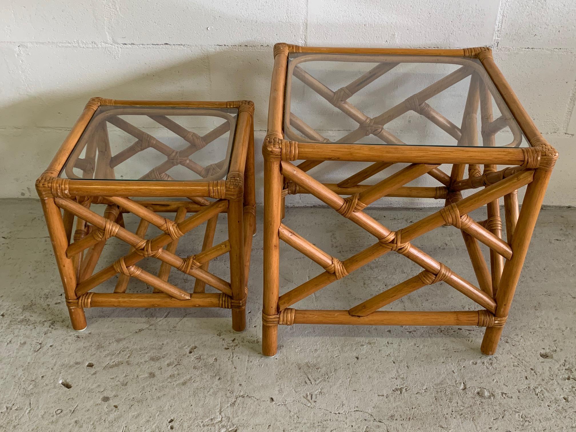 Rattan nesting tables feature Chinese Chippendale design and glass tops. Good vintage condition with minor imperfections consistent with age. Large table measures: 17