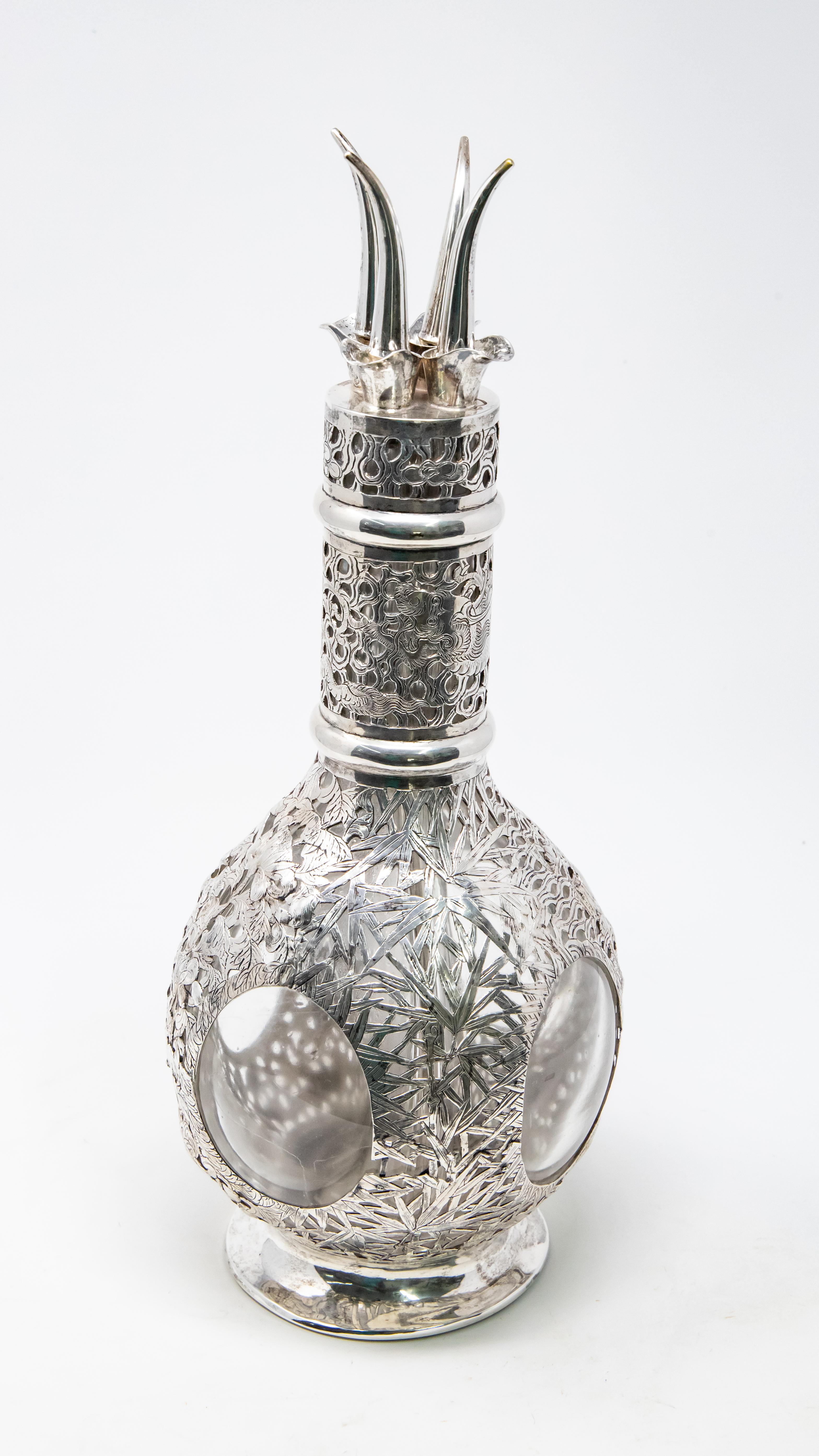 Silver over glass decanter from the late 1800. Beautiful sterling with a floral motif surrounds a decanter that is divided in four sections. At the top four stoppers are curved and come to a point.
