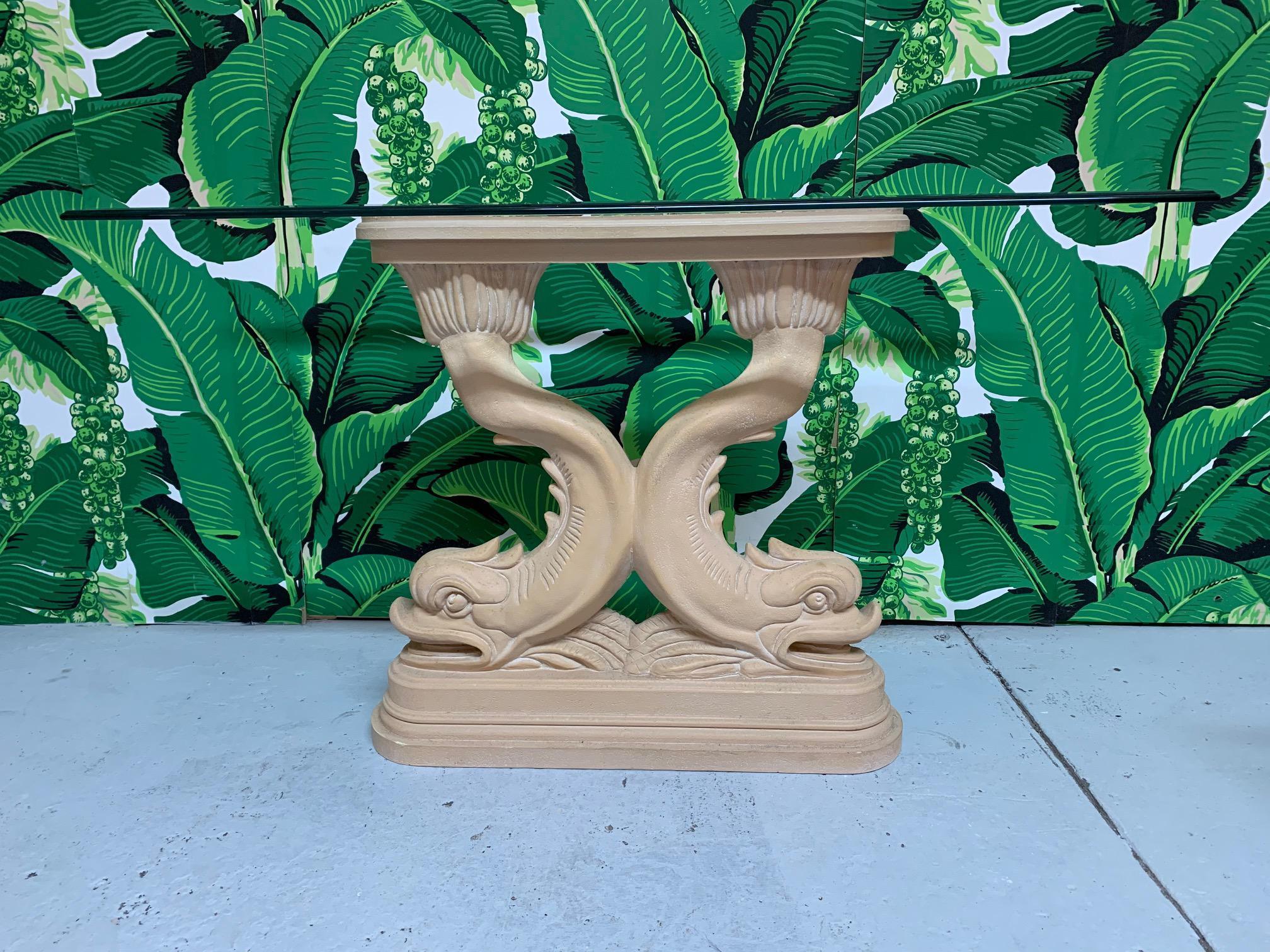 Sculptural Chinoiserie console table features a pedestal of twin Asian dolphins holding a beveled glass top. Cast plaster base. Very good vintage condition with very minor imperfections consistent with age. Glass measures 46