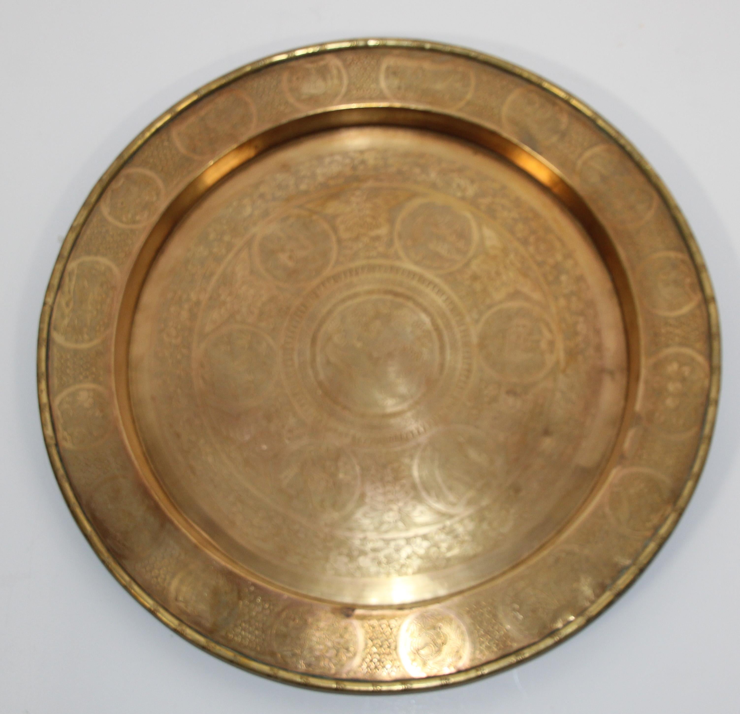 Asian antique round brass tray.
The handcrafted circular metal brass platter is decorated and hammered with Asian designs.
Heavy brass plate with very fine hand chased floral and geometric Asian designs and animal scene figures, dragons in the