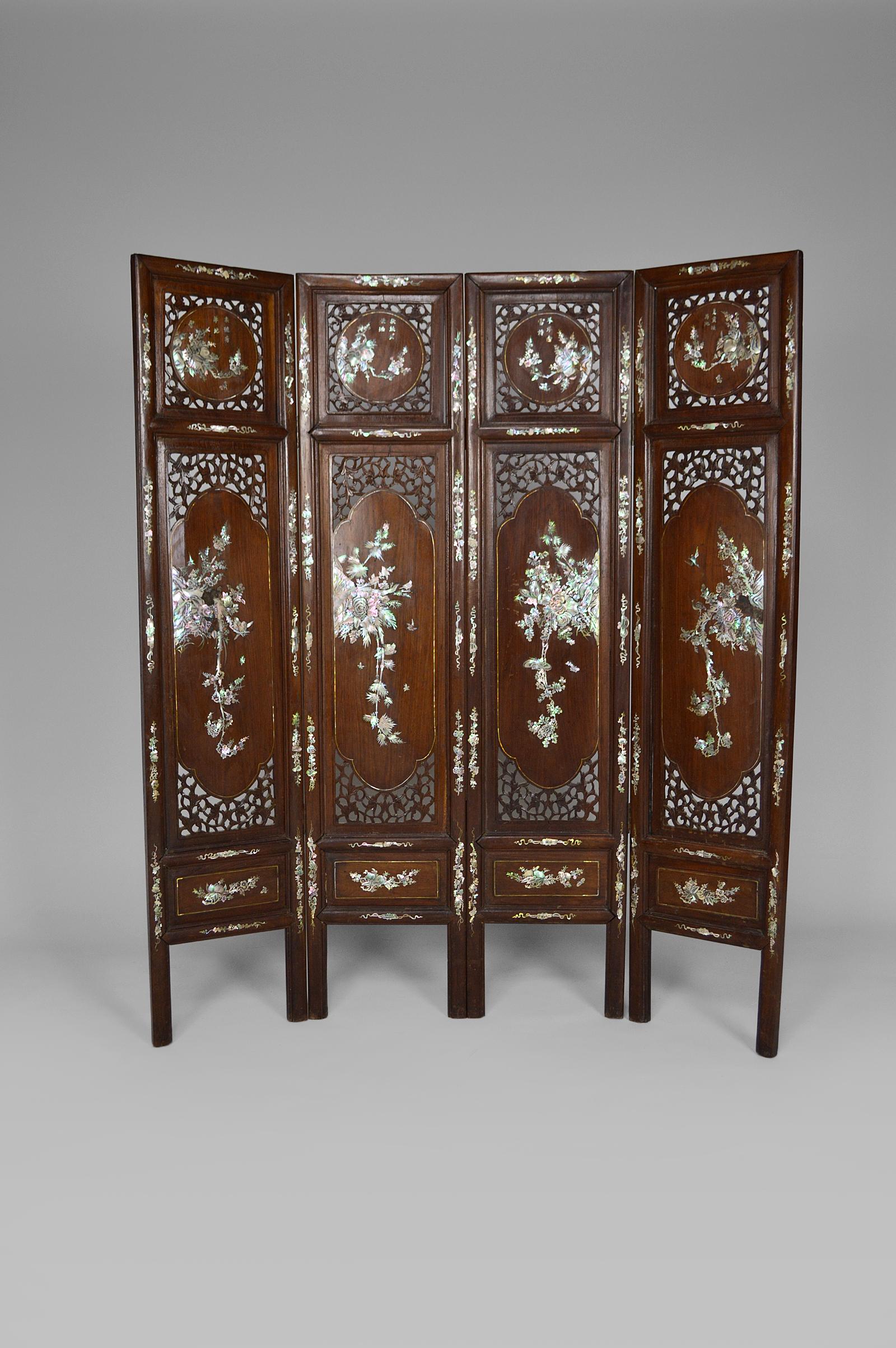 Paravent décoratif à 4 panneaux en bois sculpté, ajouré et incrusté de nacre.
Les motifs de marqueterie sont de bonne qualité, sur le thème de la faune et de la flore : représentation de fleurs, fruits, oiseaux, papillons...

Ancienne Indochine