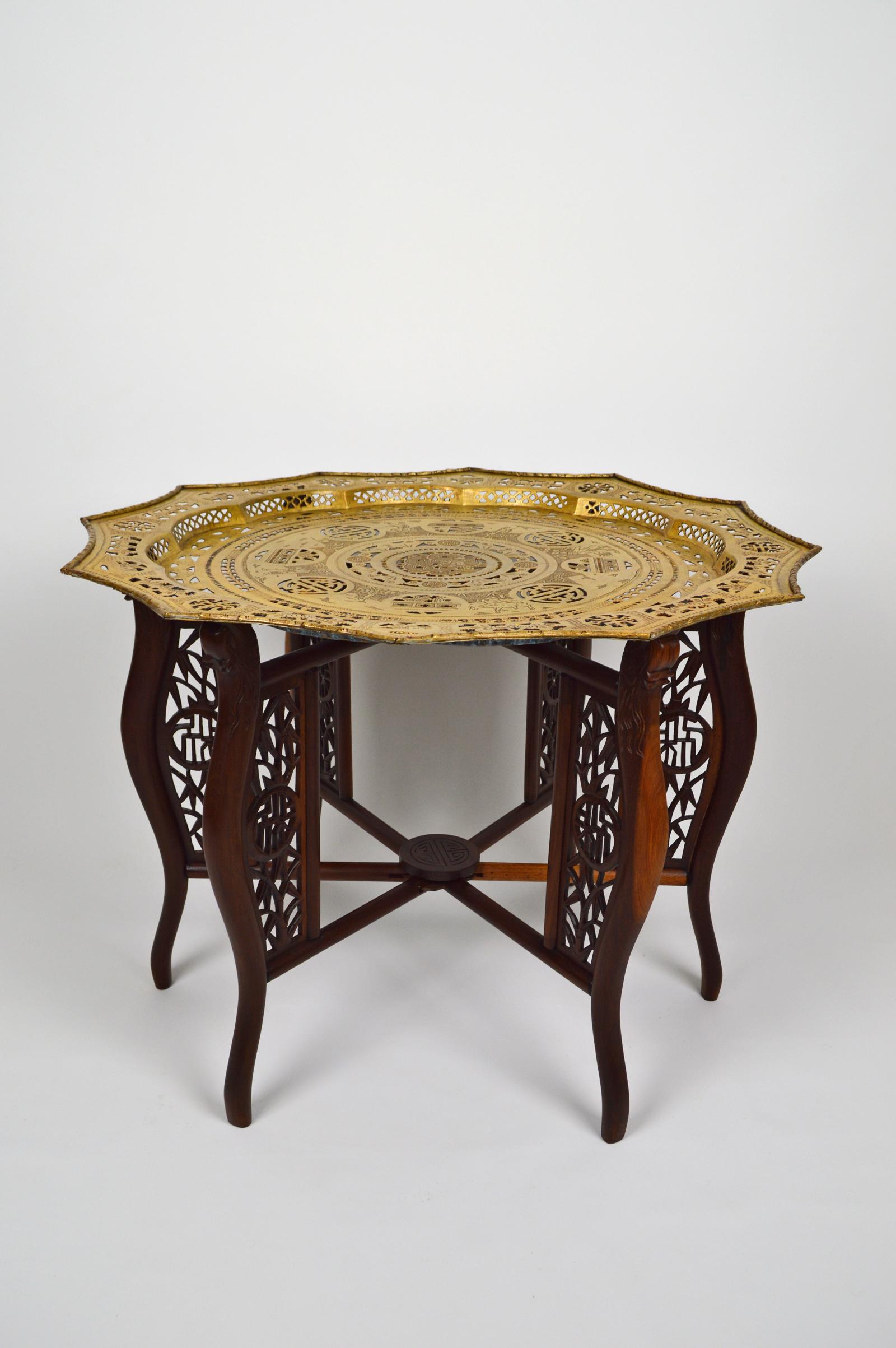 Nice Asian coffee or tea table in two parts:

- a solid wood folding base carved with dragons, bamboos and medallions / symbols ;
- a tray in bronze patinated brass. Richly decorated, with scenes of village life: a fisherman, two farmers, one