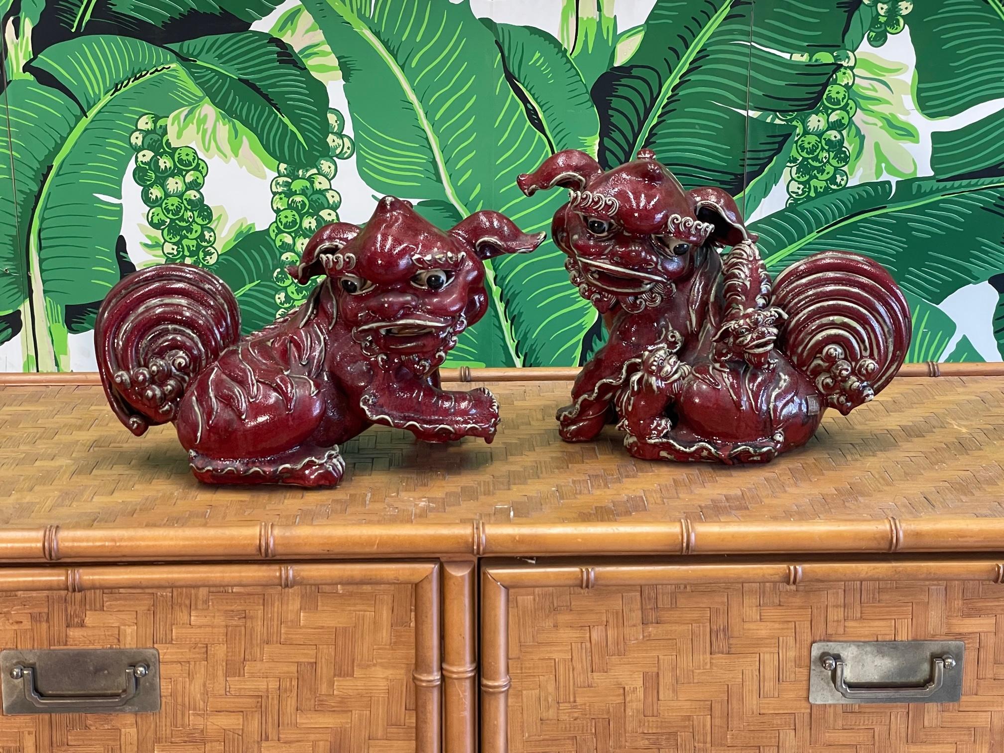 Pair of foo dog statues, father and mother carrying babies finished in cinnabar red. Good vintage condition with imperfections consistent with age and with hand made sculptures such as these. Mother has a cracked ear but is structurally sound. See