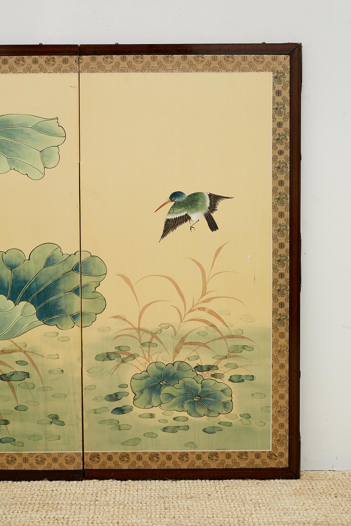 Delightful Asian four panel Byobu screen depicting a water scene of flora and fauna. Large green lily pads dominate the foreground with delicate flowers and small birds. Painted with soft feminine colors and set in a contrasting dark wood frame with