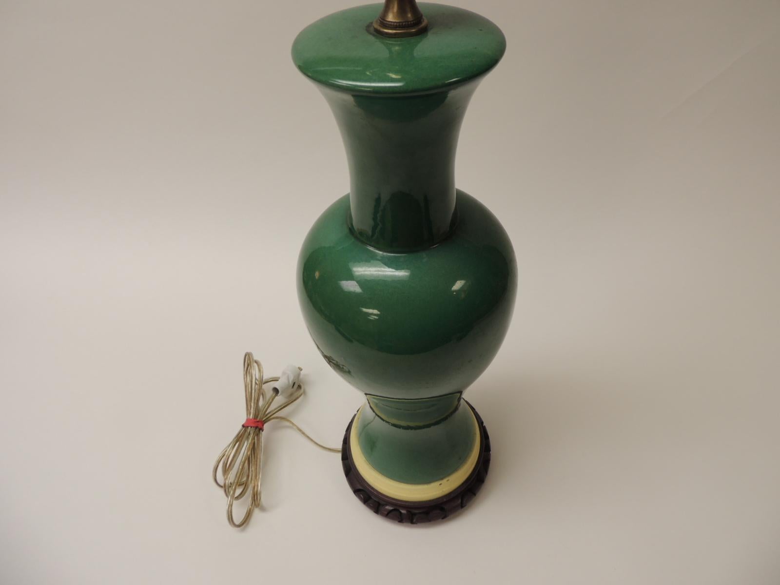 Asian ginger jar shape green vintage ceramic lamp with brass fittings (no harp or lamp shade)
Sits on a painted brass base and a carved wood base.
Size: 23 H x 6D, 
1970s, Asia.
  