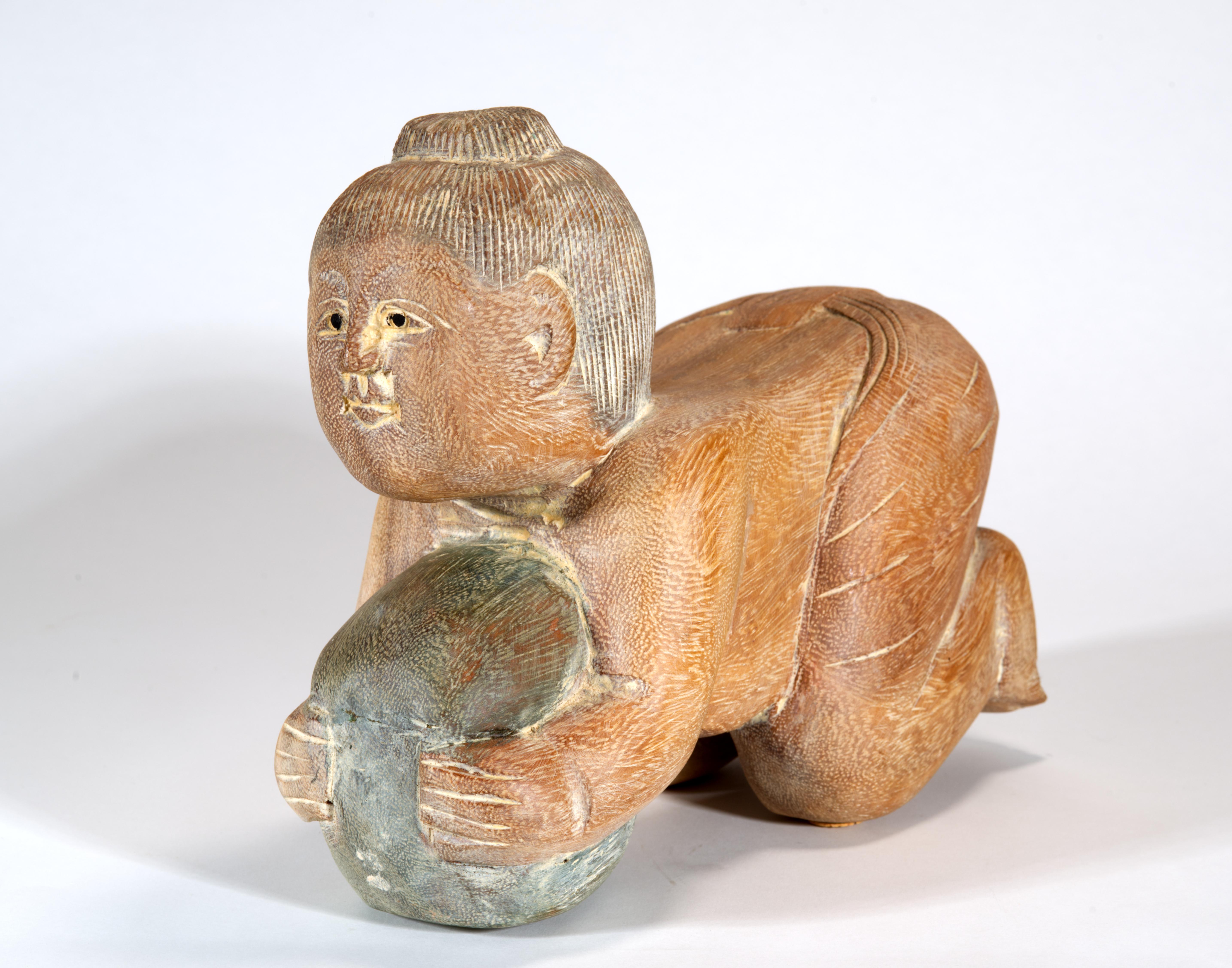 La escultura vintage de Buda bebé, tallada y pintada a mano, representa a Buda de niño, arrodillado y abrazando un gran melón, listo para dormirse. La pose del bebé recuerda a las almohadas de madera chinas de estilo Ming, pero el tamaño y la