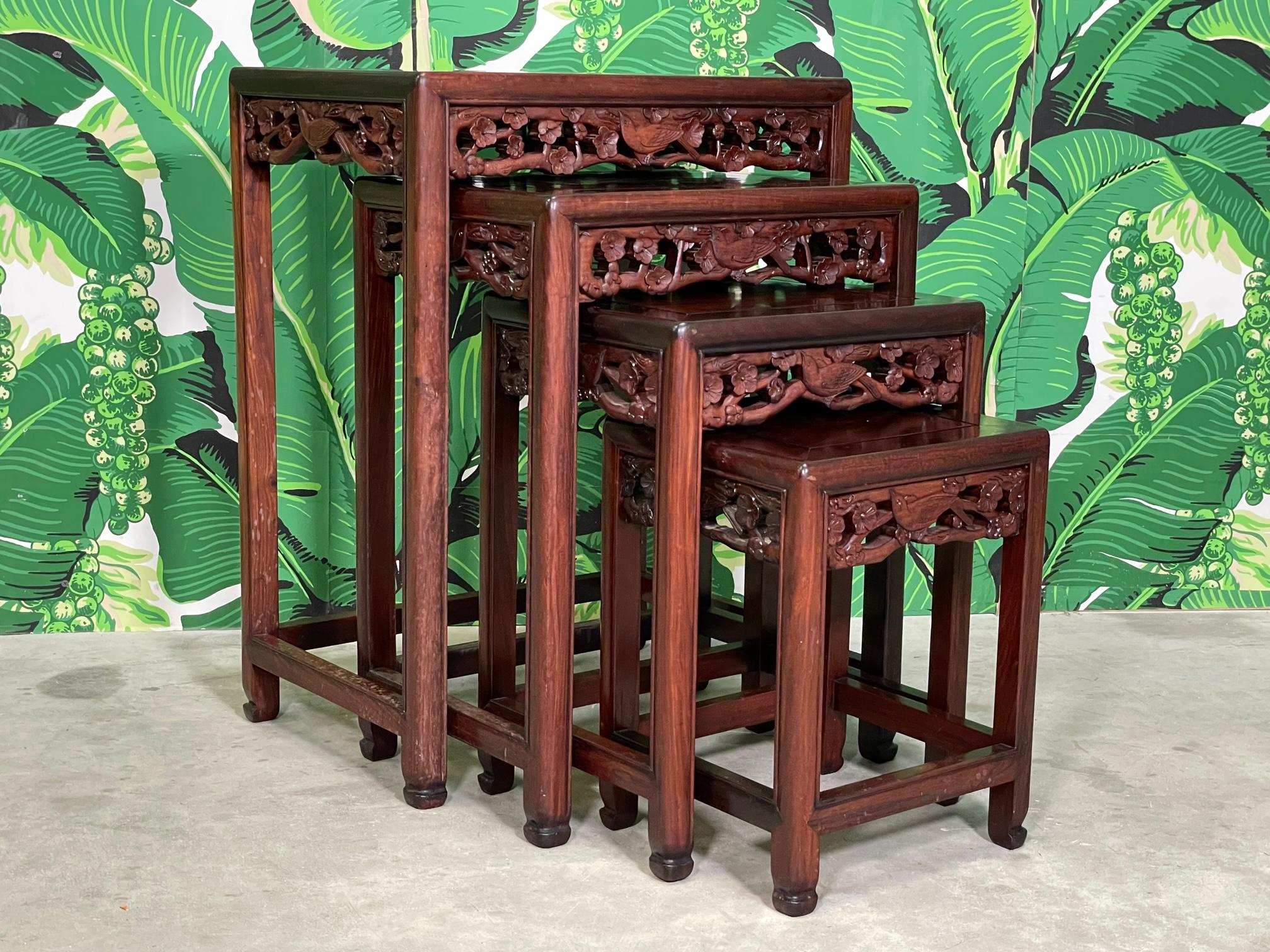 Set of four Asian modern exotic wood nesting tables or stacking tables feature hand carved friezes with birds and flowers. Good condition with minor imperfections consistent with age. Some discoloration on top of largest table. Pieces may exhibit