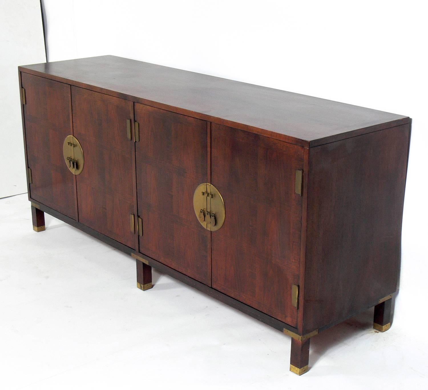 Asian inspired credenza, designed by Michael Taylor for Baker, American, circa 1960s. It offers a voluminous amount of storage with the left double doors opening to reveal a storage area with an adjustable shelf, and the double doors on the right