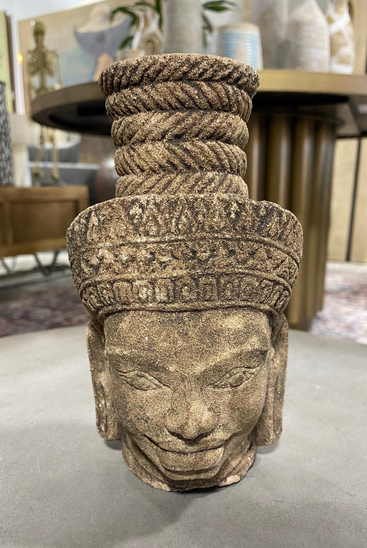 A wonderfully sand stone-carved Asian deity figure / sculpture likely from Cambodia. The detailed head is likely that of the divinity deity Shiva, sometimes referred to as the smiling God-King. The features are clearly reminiscent of the carvings