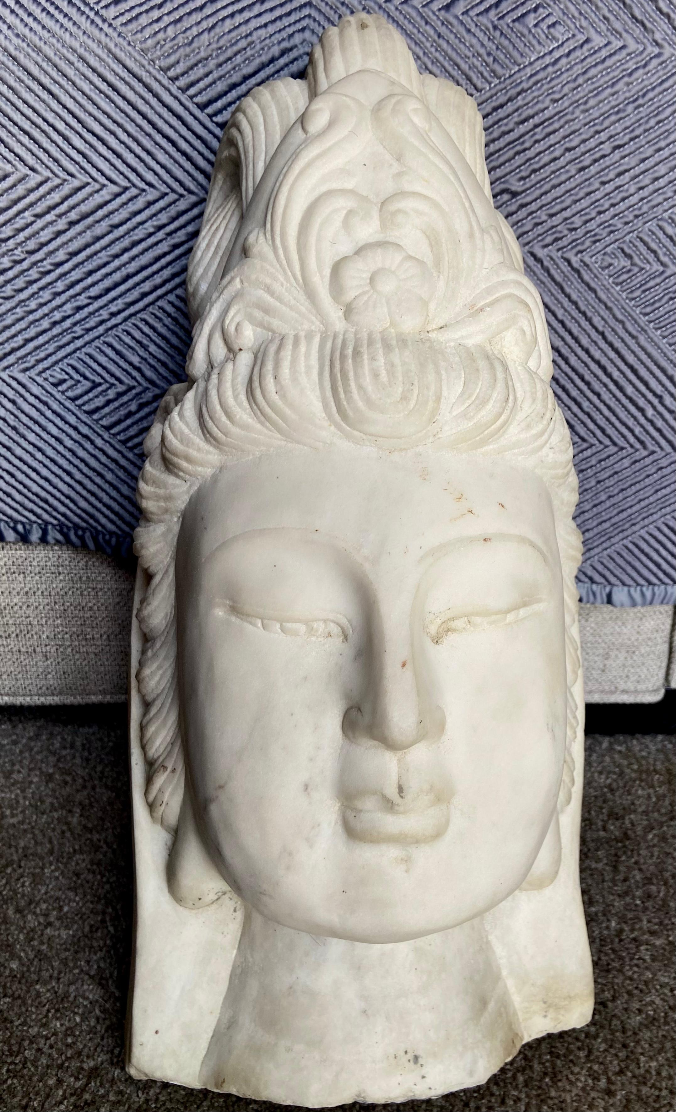 Beautifully executed hand carved marble buddha head fragment of Quan Yin. The youthful face is peaceful and serine framed by an intricately carved headdress. A striking art object with fine quality workmanship. This is an older piece most likely