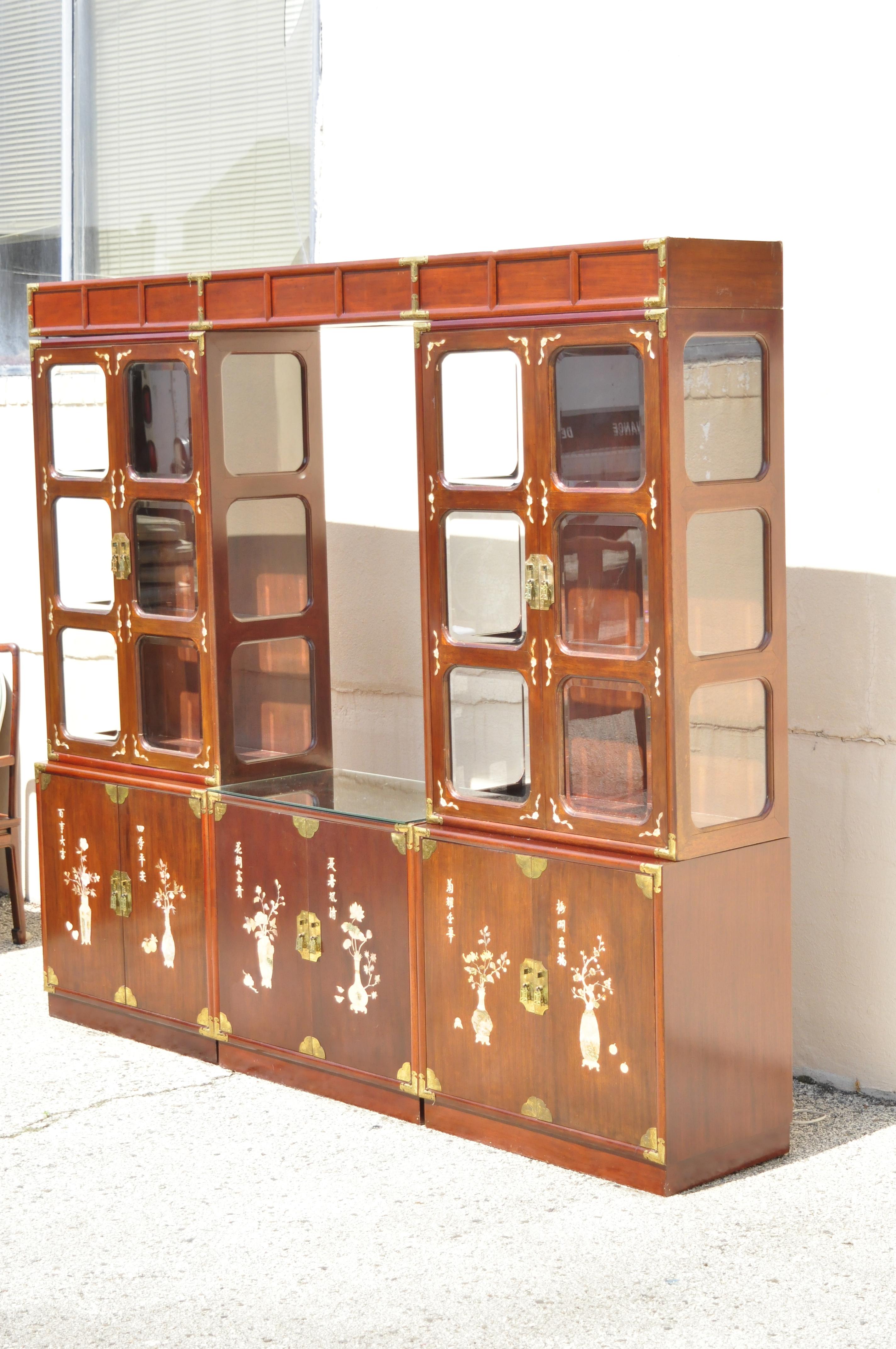 Asian mother of pearl rosewood cherry large China cabinet curio display wall unit. Item features large impressive size, mother of pearl inlay throughout, 2 upper display cabinets, 3 lower storage cabinets, one cabinet with 3 drawers, upper pediment
