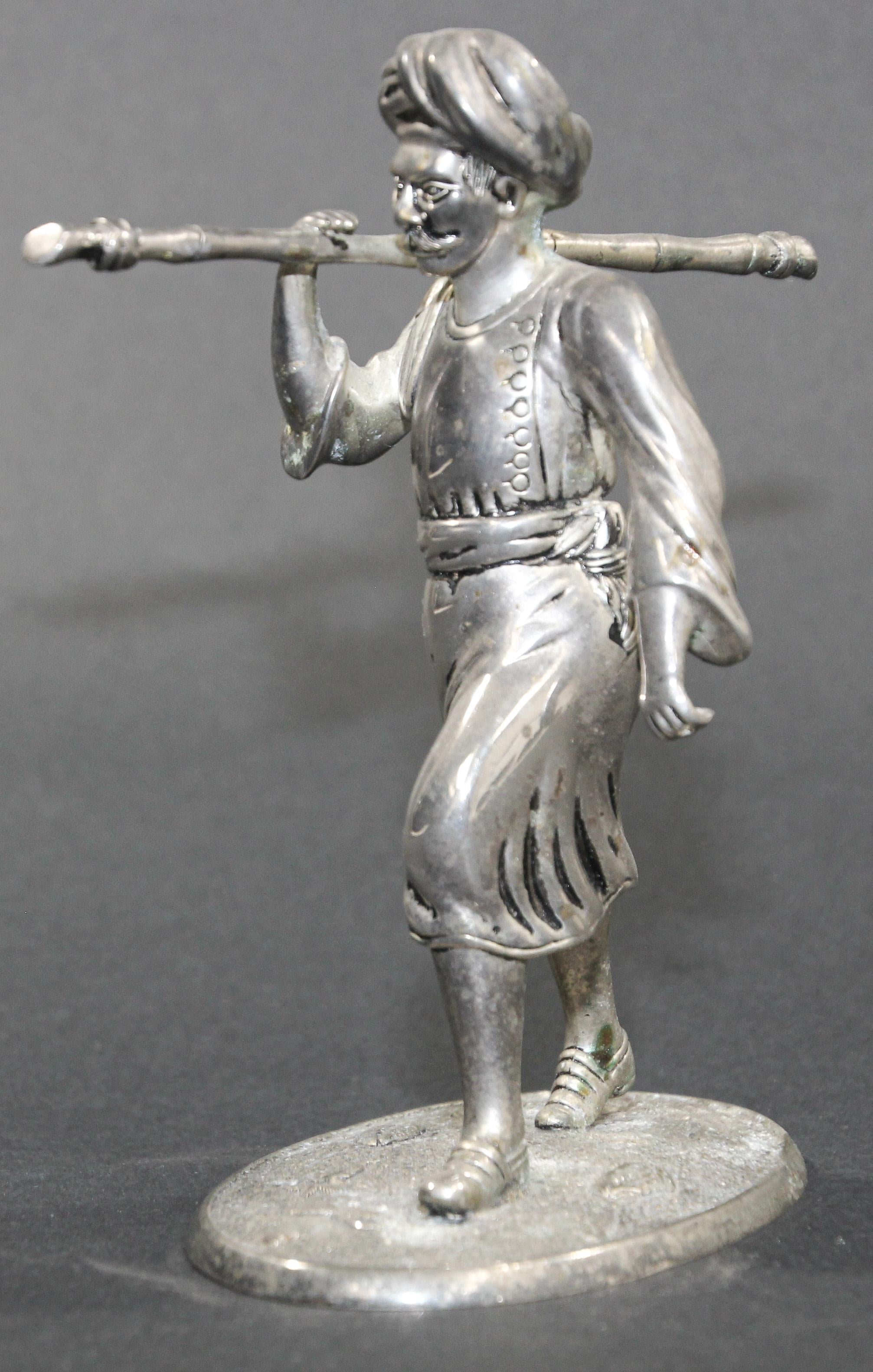 Silver plated sculpture of an Asian Indian farmer peasant man walking holding a long cane.
Sculpture of an old Indian farmer wearing traditional clothes and a turban.
     