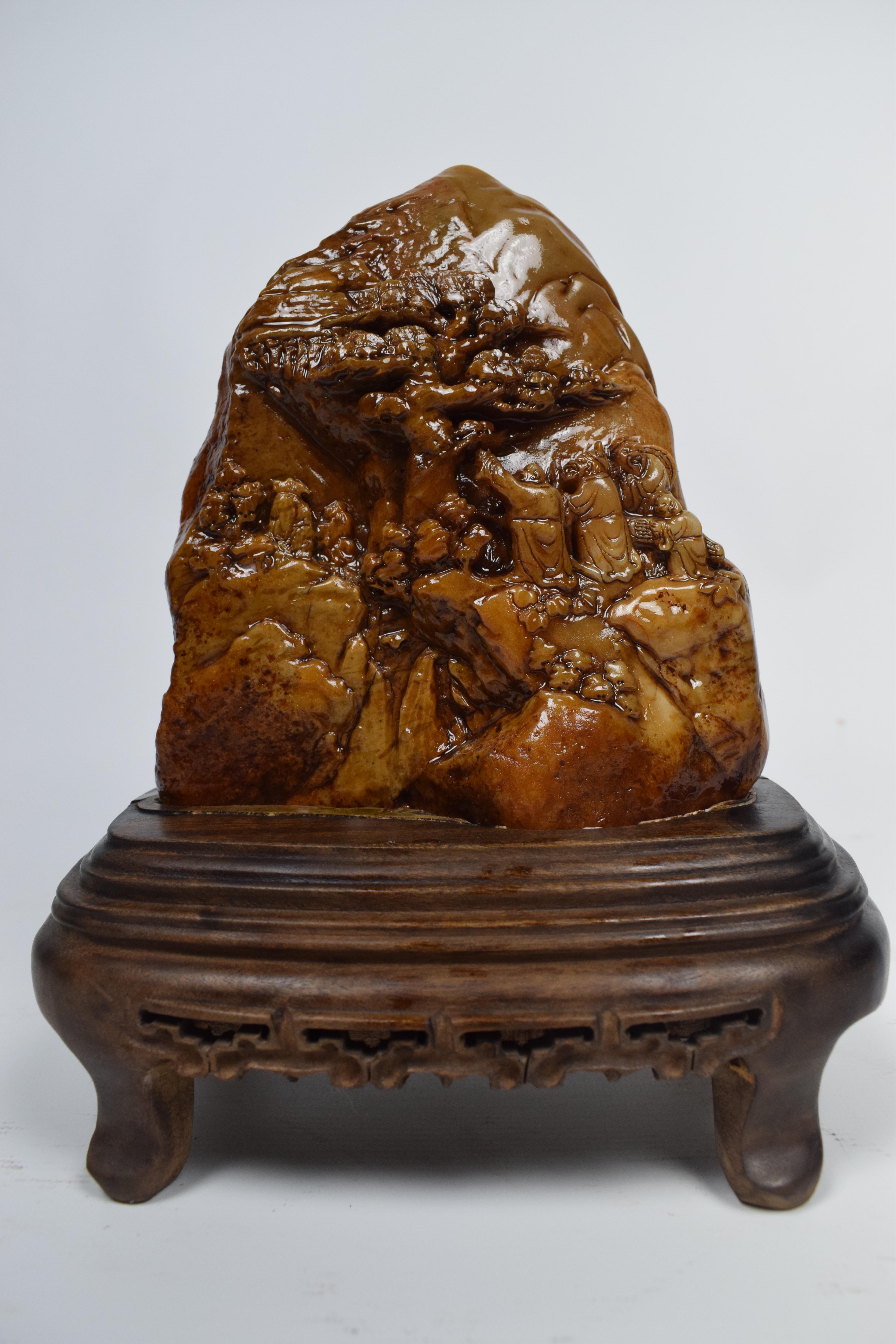 The Chinese mustard soapstone carving from the mid-20th century, depicting a village scene centered around a tree, is a captivating piece of art with a distinct color palette and a focus on nature and community. Mustard soapstone, known for its warm
