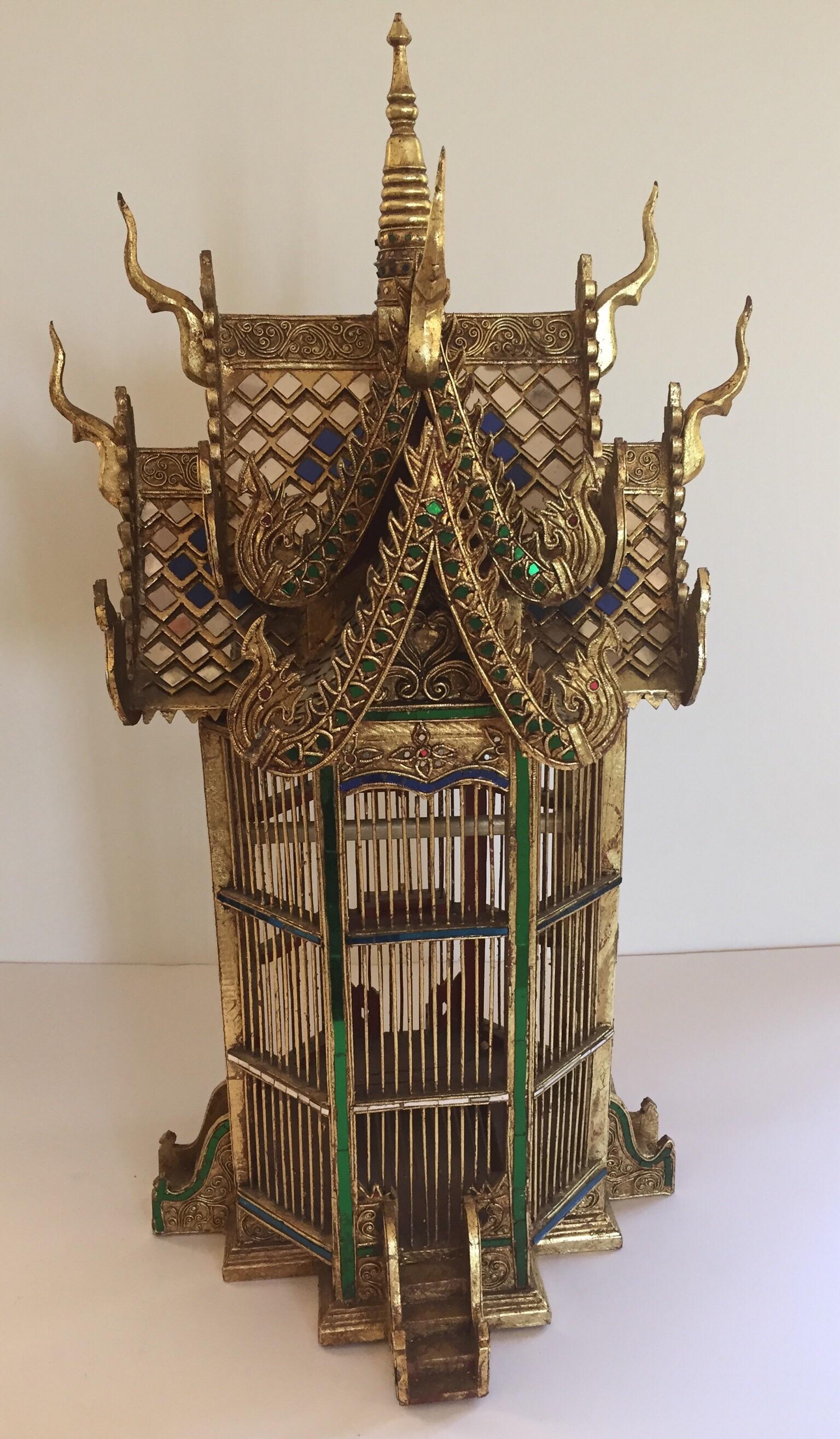 Great architectural miniature of an Asian Thai temple with extremely elaborate hand carved details.
Amazing handwork, gilt wood with delicate carving shrine bird cage handcrafted and hand-painted spirit house shrine made into a bird cage.
Hand