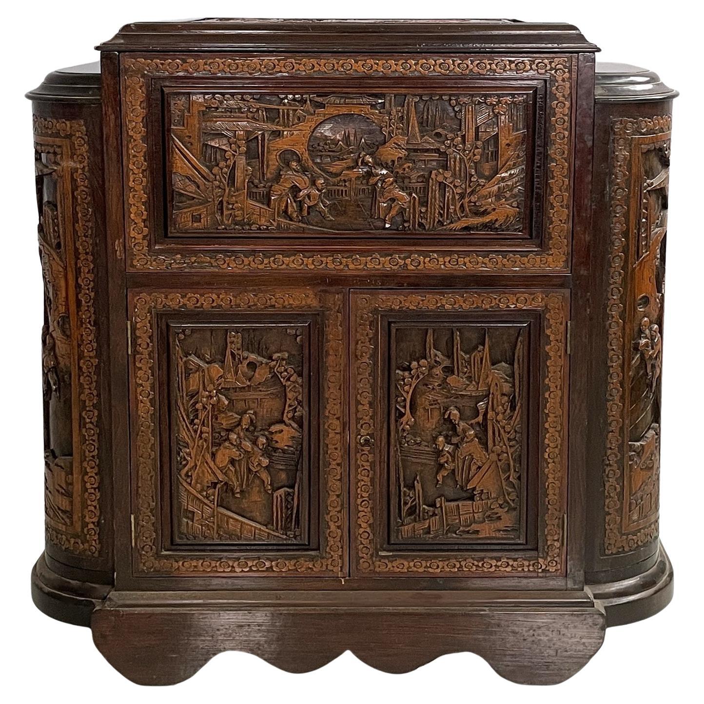 Mueble bar Art Decó de estilo asiático con incrustaciones de madera, años 30
Mueble bar totalmente en marquetería de madera, de hecho en las caras frontales hay tallas que representan escenas con un marco de flores. En la parte superior hay un
