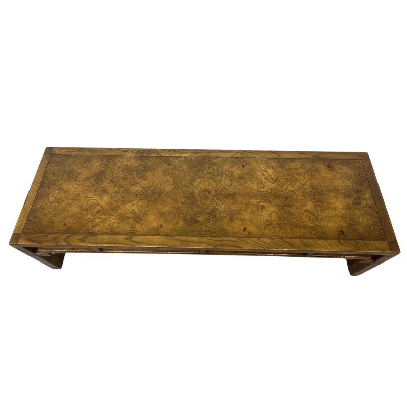 An Asian style coffee table from the Artefacts for Henredon collection.  A banded border of burl wood is featured on the top and the rounded square legs and create open sides with a grid design to the apron adding to the Asian aesthetic.   A