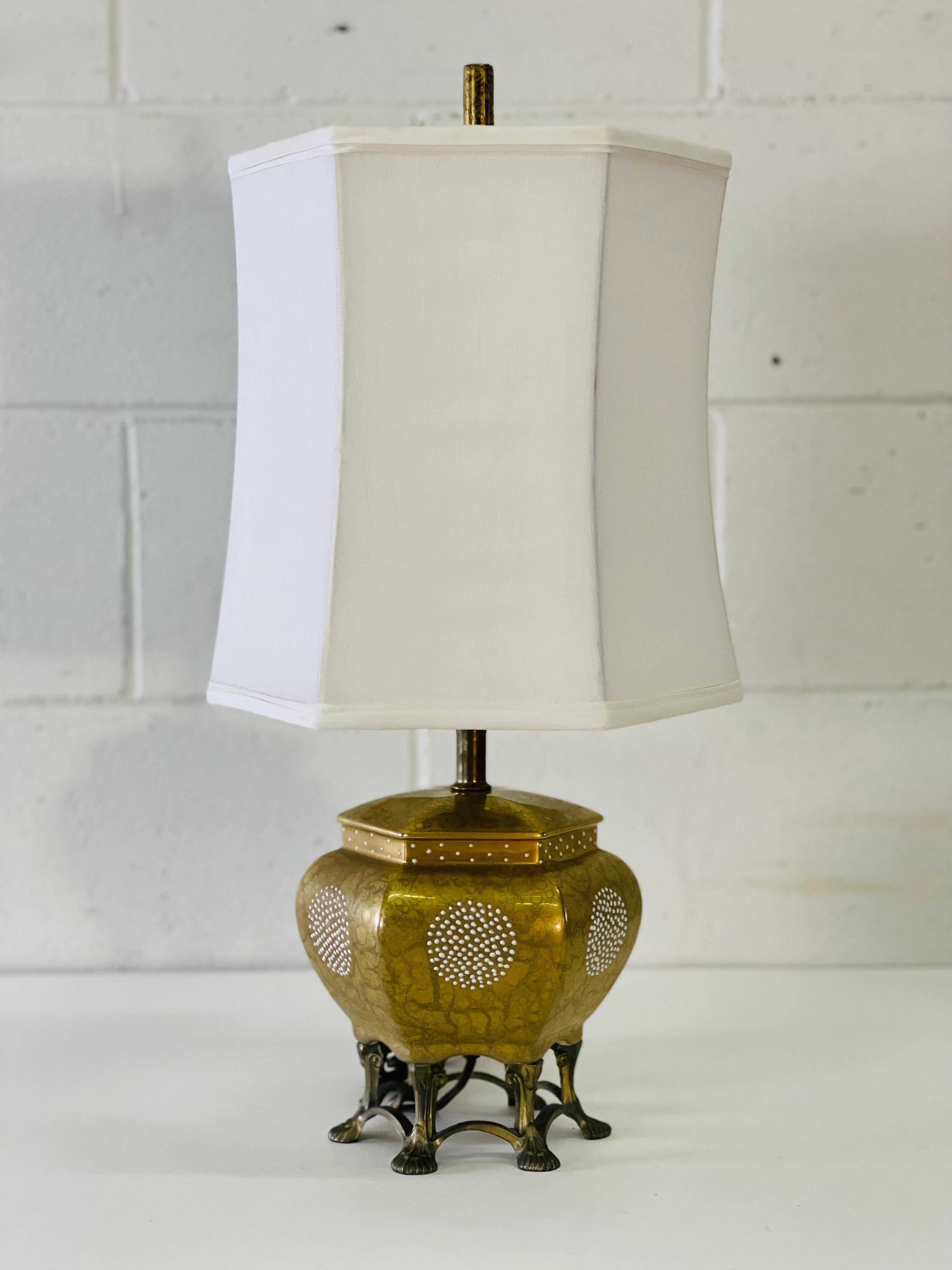 Vintage 1950s Asian style table lamp and shade with a brass claw foot base and ceramic body. The body of the lamp is gold with white accented dots. The shade is white linen. Wired for the US and in working condition. Socket, 12”H. Harp, 4” diameter