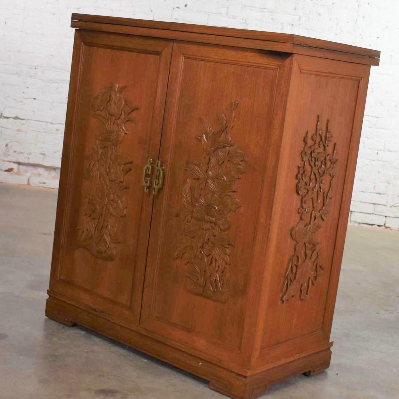 Handsome chinoiserie or Asian style dry bar in a box. The sides and top fold out expanding this cabinet to double its width. Adorned with six panels applied with carved birds and flowers. It is in fabulous vintage condition with no outstanding flaws