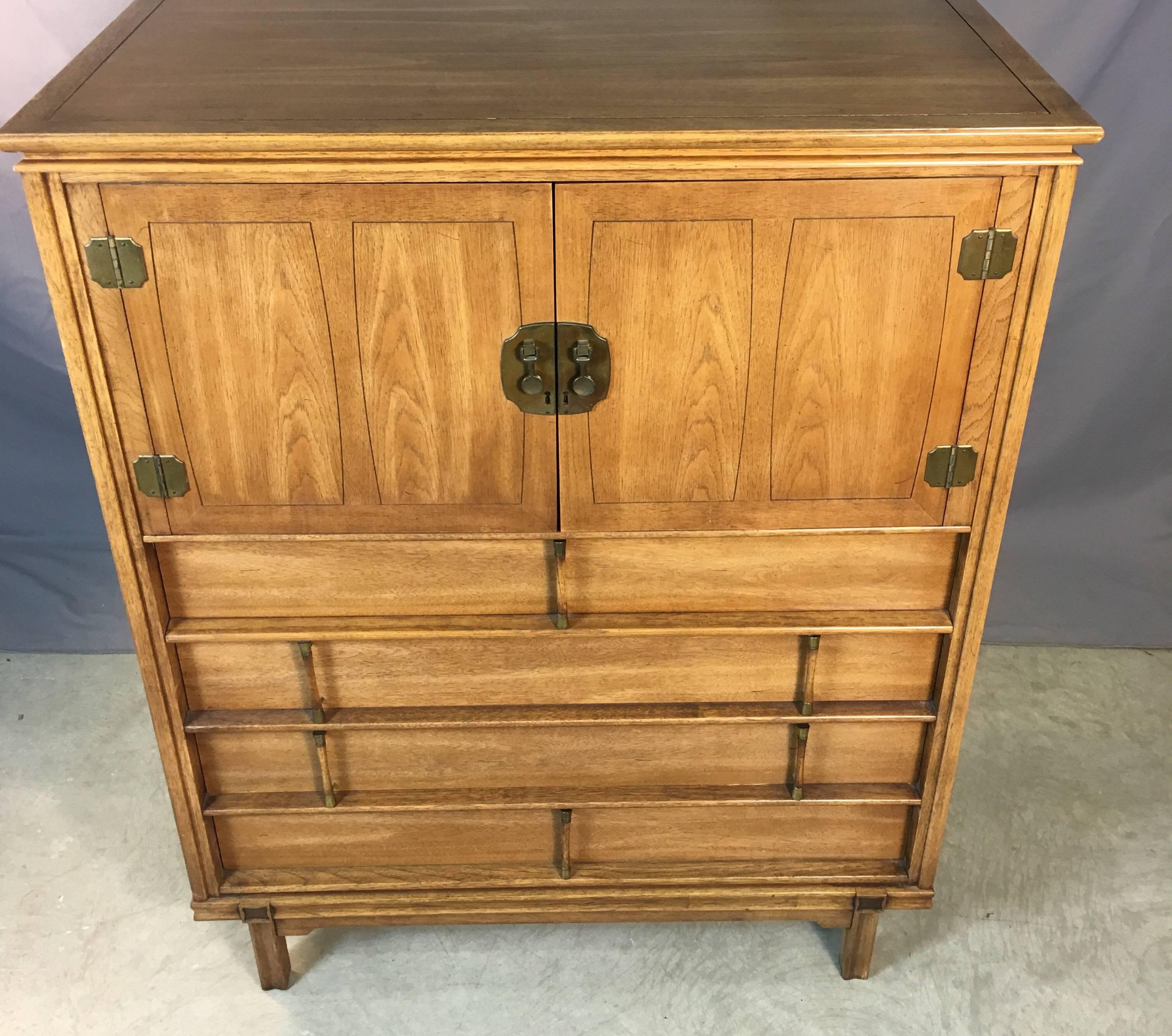 Mid-Century Modern, 1960s Asian-style solid mahogany five drawer tall highboy dresser with brass accented pulls. The dresser has three drawers on the bottom and two more behind the doors. Excellent used condition. No marks.