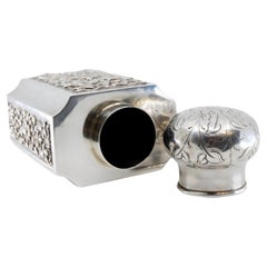 Asian-style silver perfume bottle with engraved lid and relief casing