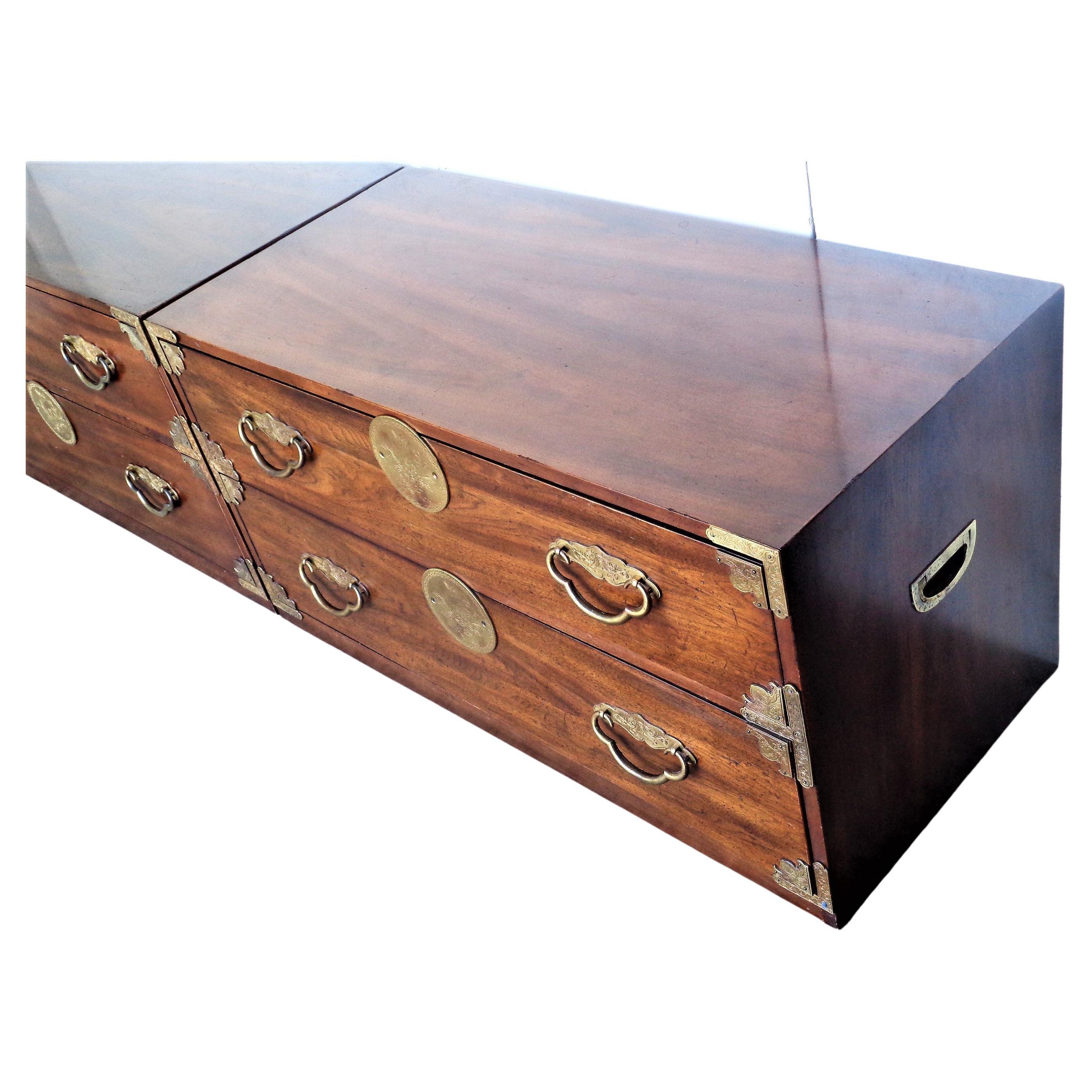 A great looking pair of Asian modern style two drawer campaign bachelor chests with decorated brass fittings on front and brass swing handles at both sides. Use separately as side chests, the two together as a low long chest / stacked as a four